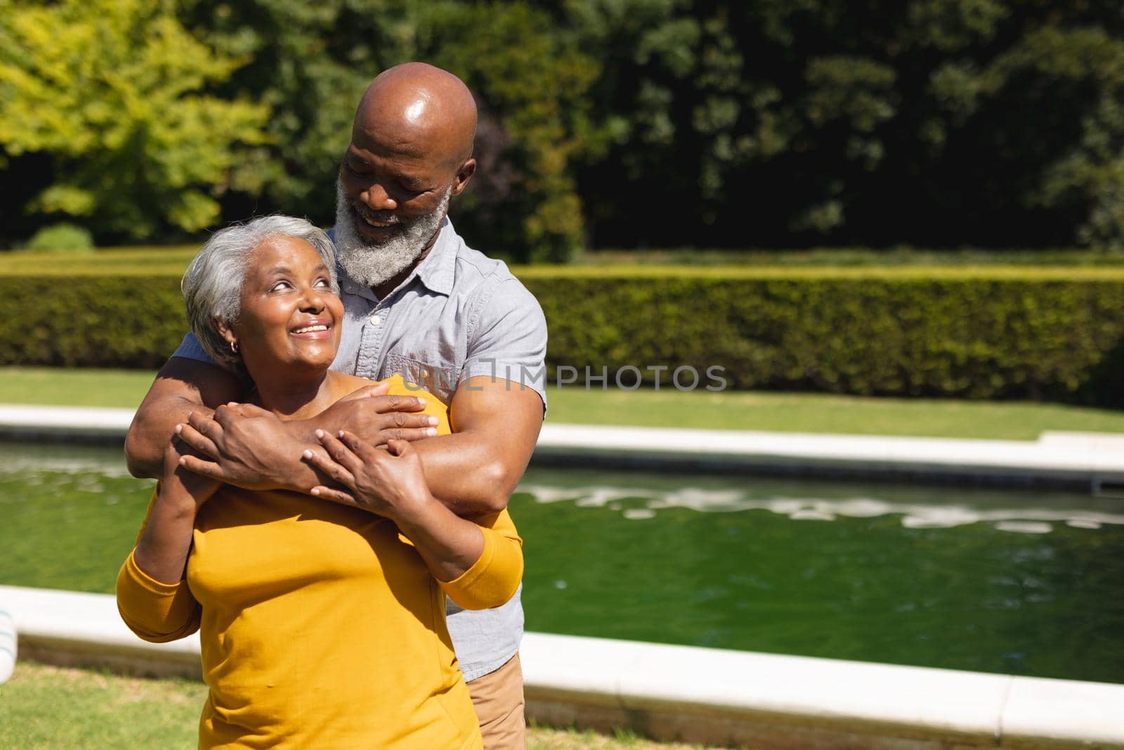 Senior african american couple spending time in sunny garden together embracing and smiling. retreat, retirement and happy senior lifestyle concept.