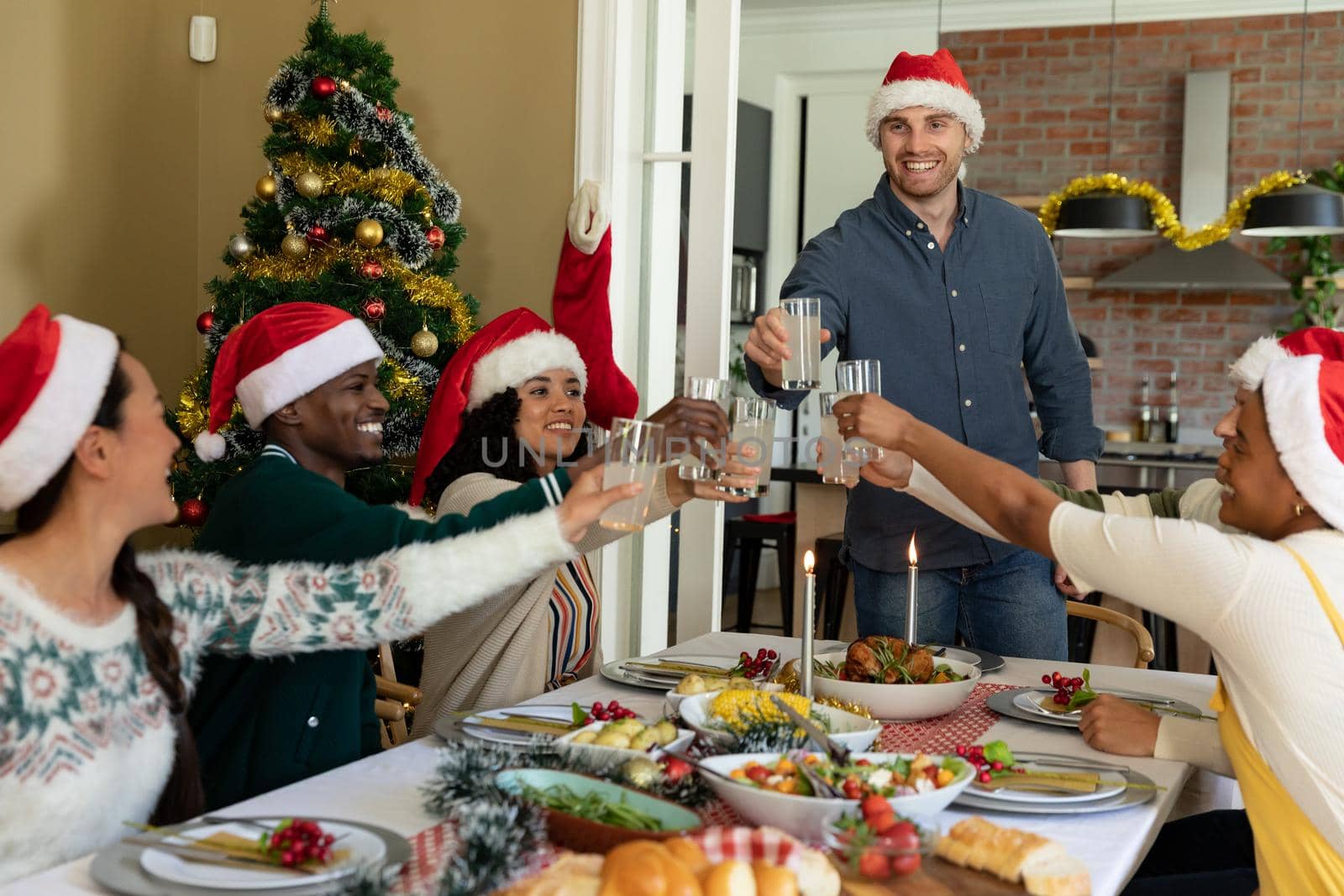 Group of happy diverse female and male friends toasting, celebrating christmas at home. christmas festivities, celebrating at home with friends.