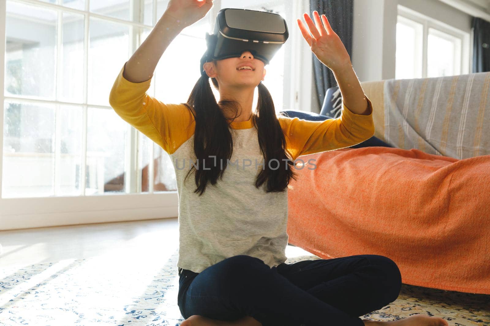 Asian girl sitting in living room and using vr headset. childhood leisure time and discovery using technology at home.