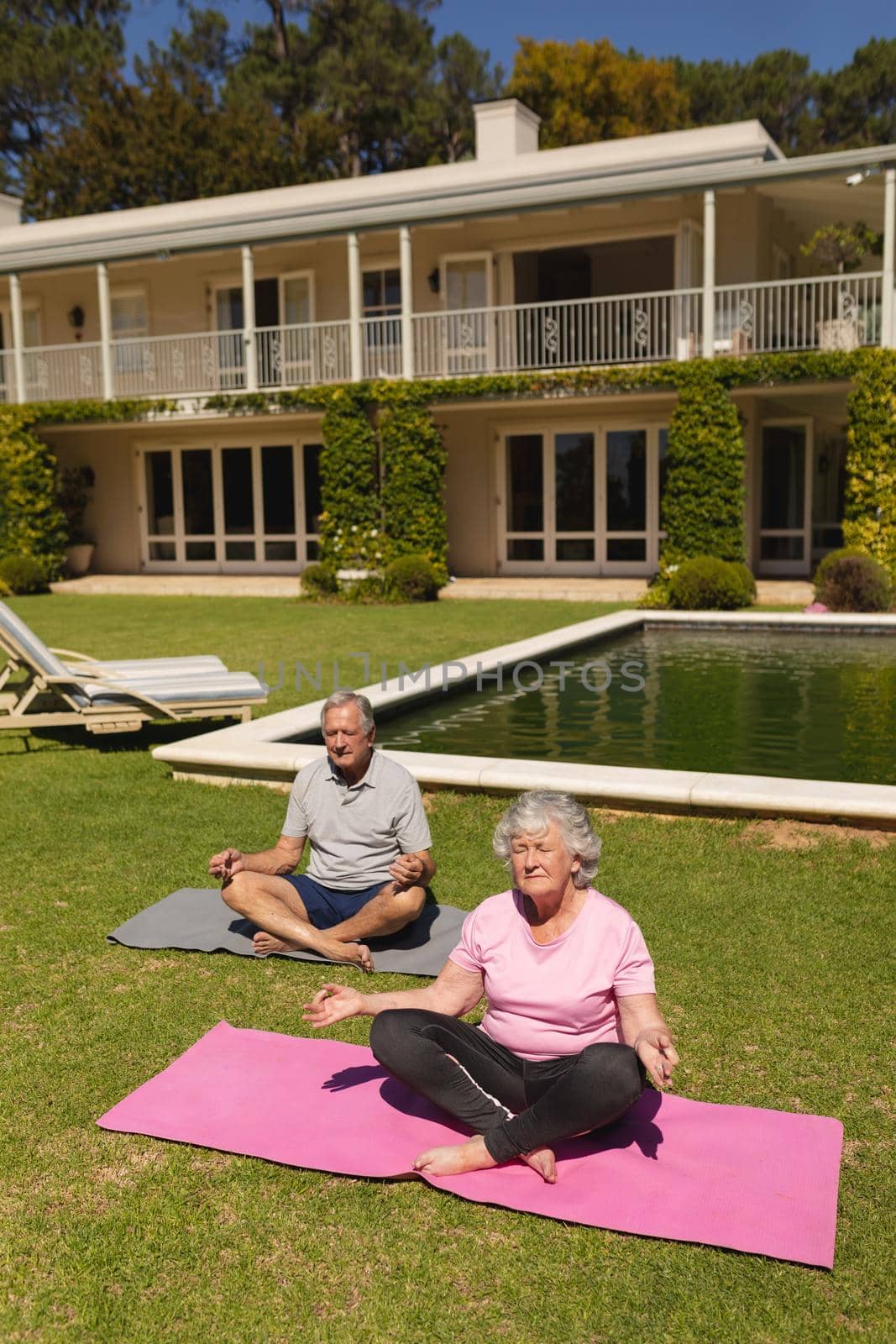 Senior caucasian couple practicing yoga, meditating in sunny garden by Wavebreakmedia