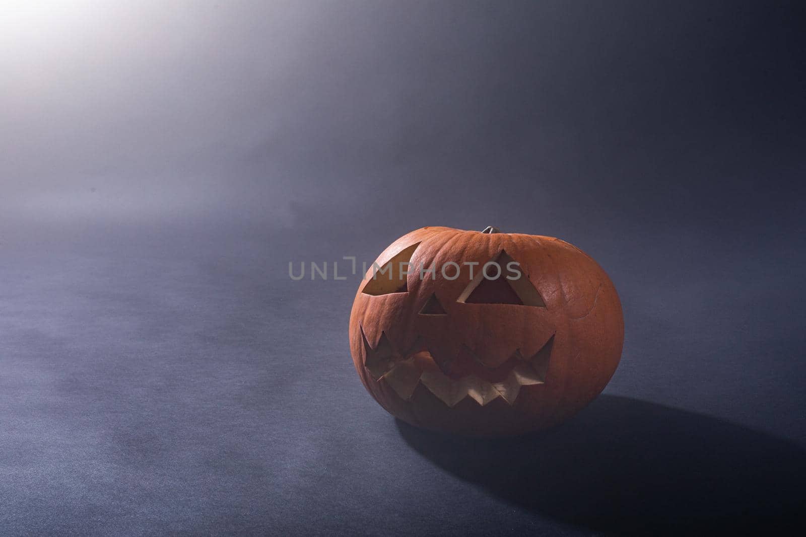 Composition of halloween carved pumpkin and cloud of smoke with copy space on black background. halloween tradition and celebration concept.