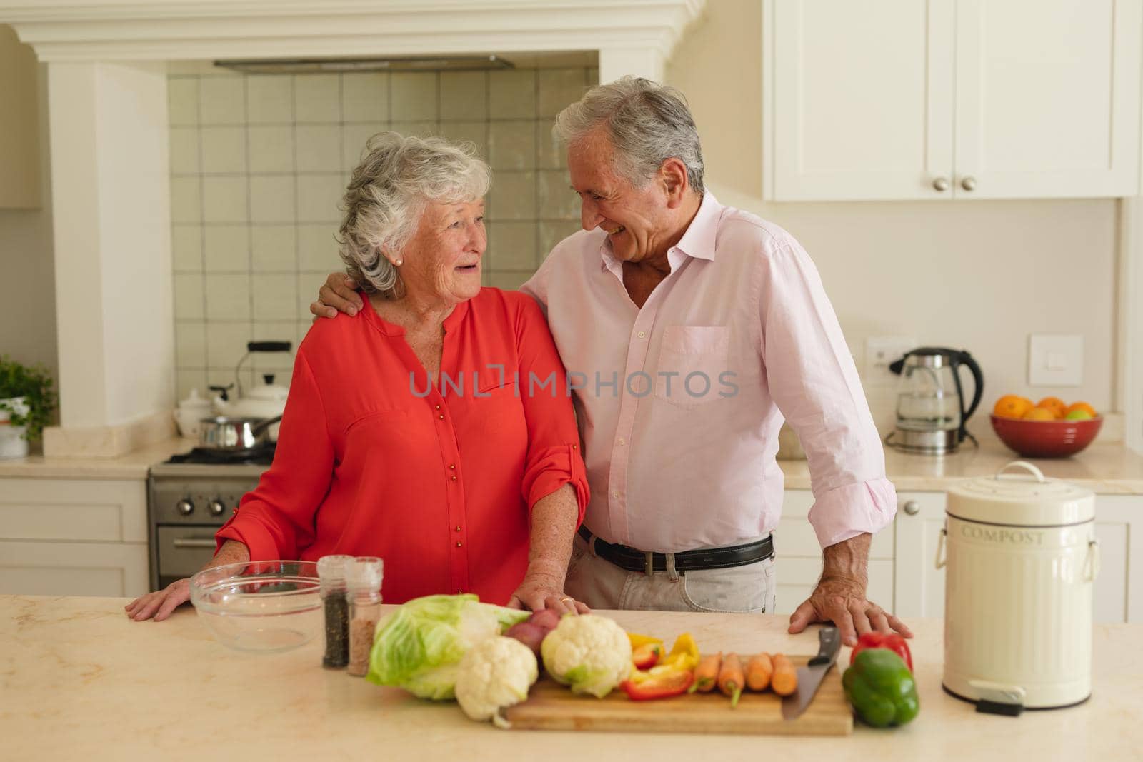 Senior caucasian couple embracing and smiling in kitchen. retreat, retirement and happy senior lifestyle concept.