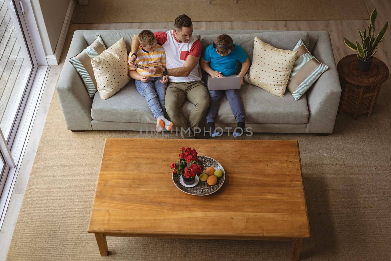 Overhead view of caucasian father and two sons using laptop and digital tablet at home by Wavebreakmedia