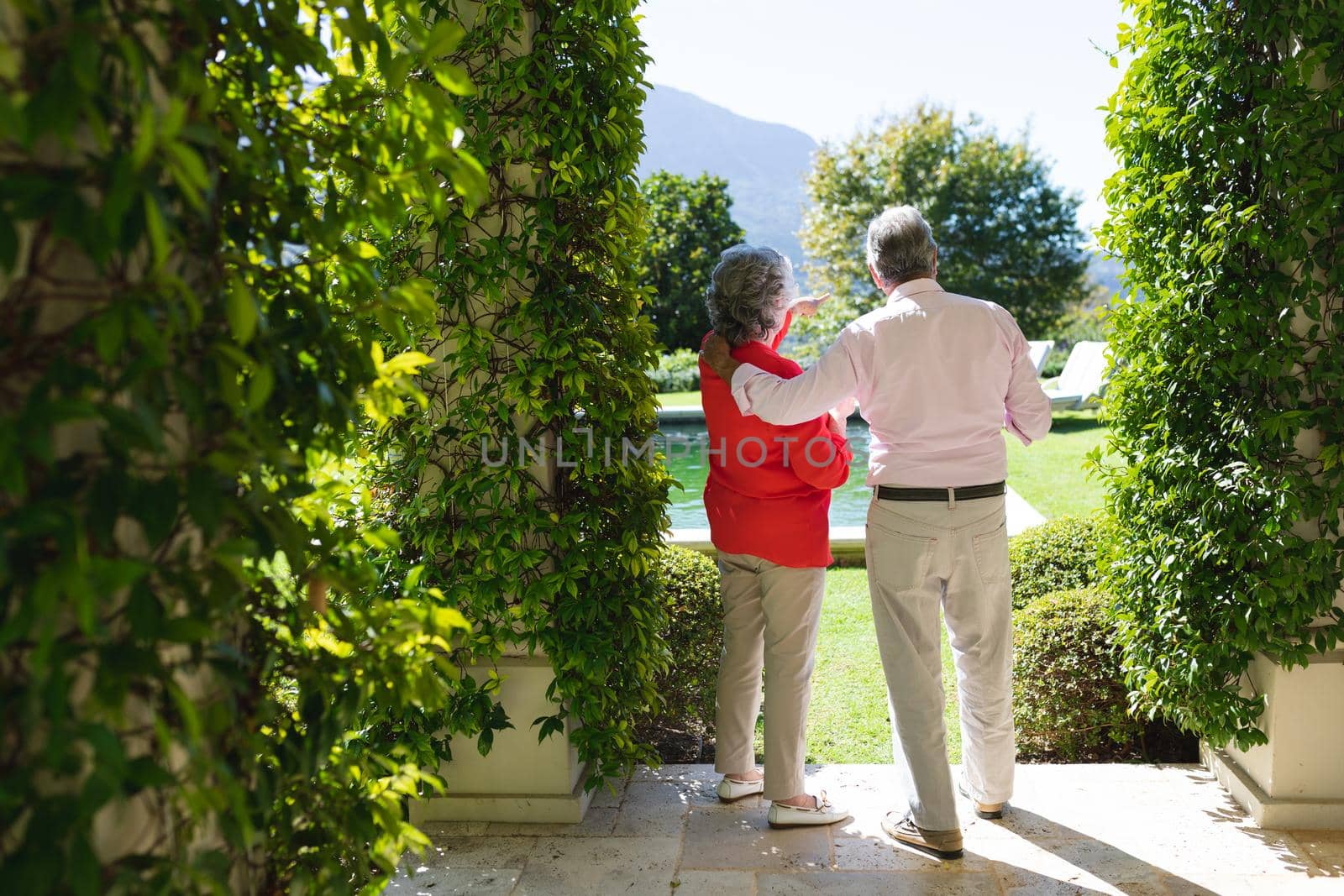 Senior caucasian couple embracing and talking in sunny garden. retreat, retirement and happy senior lifestyle concept.