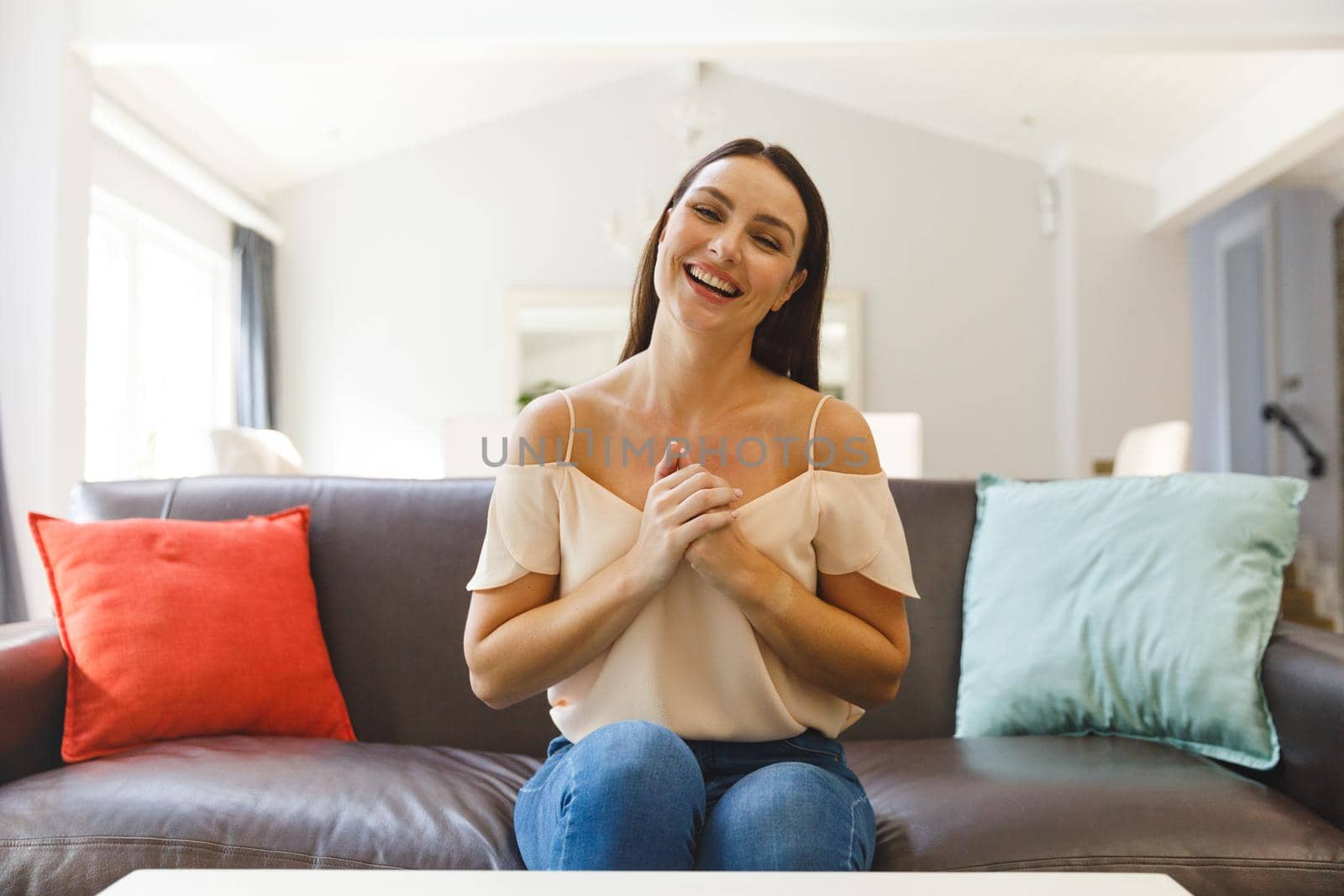Caucasian woman sitting on couch having video call in living room, smiling. keeping in touch, leisure time at home with communication technology.