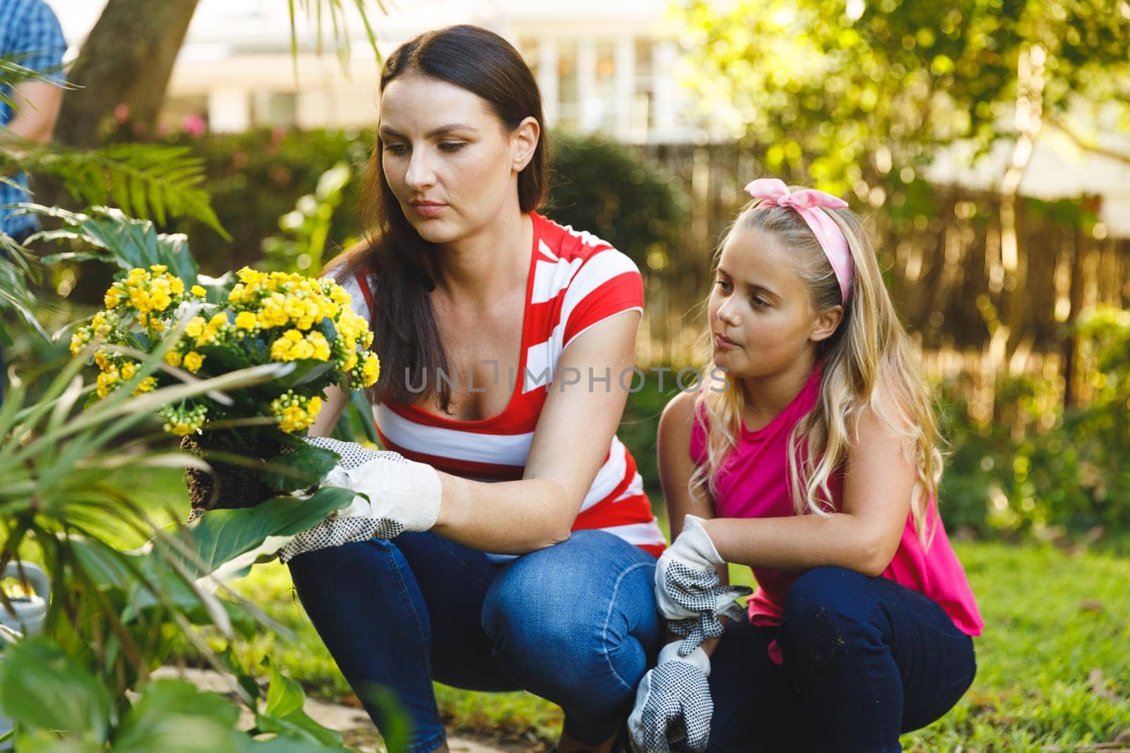 Caucasian mother and daughter working in garden wearing gloves and talking. family enjoying leisure time together gardening at home.