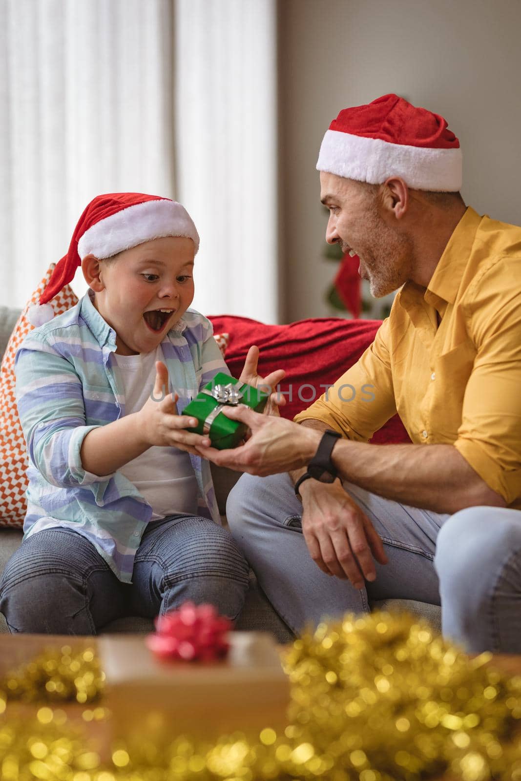 Caucasian father giving a christmas gift to his son at home during christmas. christmas festivity and celebration concept