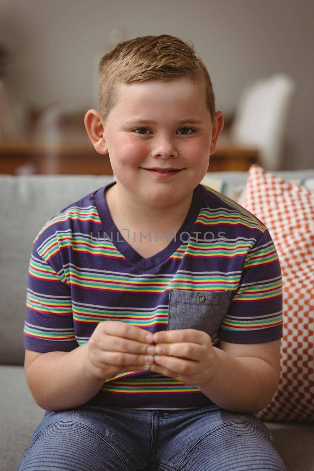 Portrait of caucasian boy making hand gestures sitting on the couch at home. sign language learning concept