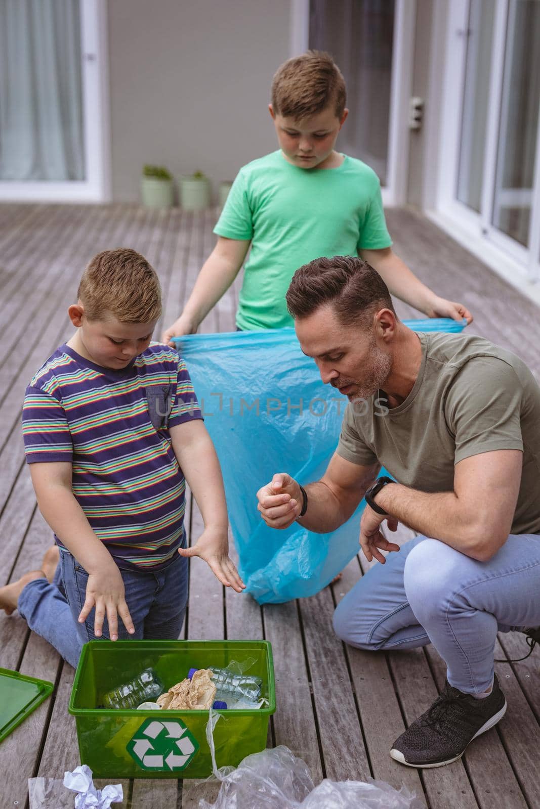 Caucasian father and two sons collecting plastic materials in a bag outdoors by Wavebreakmedia