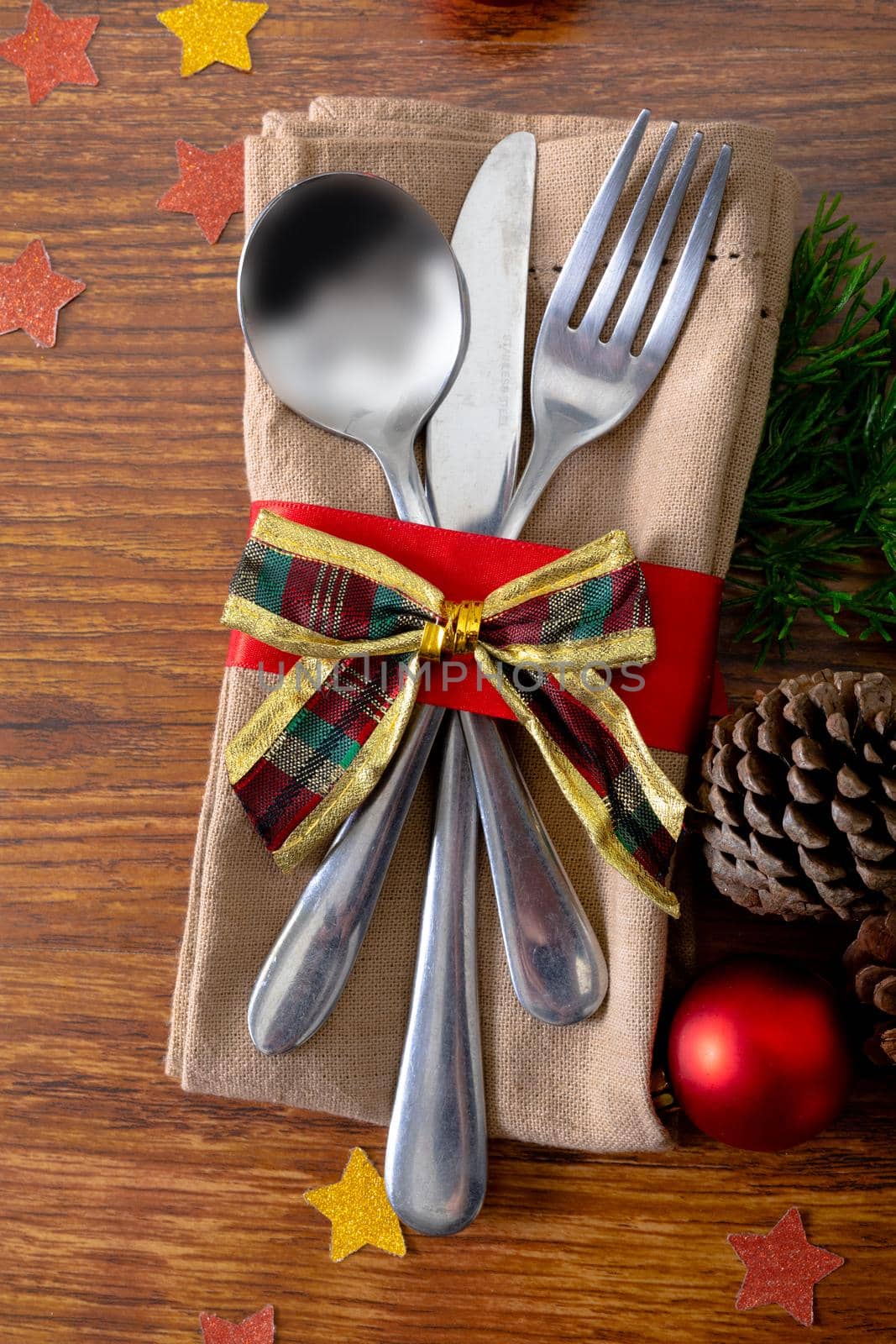 Composition of christmas decorations with cutlery and napkin tied with bow on wooden background. christmas, tradition and celebration concept.