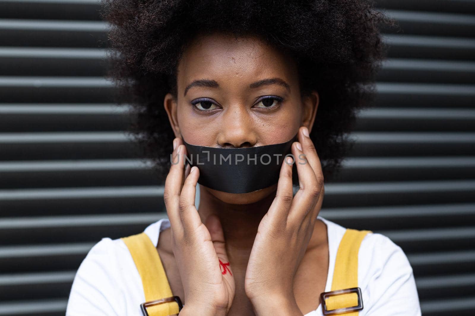 Portrait of mixed race woman having black tape on mouth. equal rights and justice protestors on demonstration march.