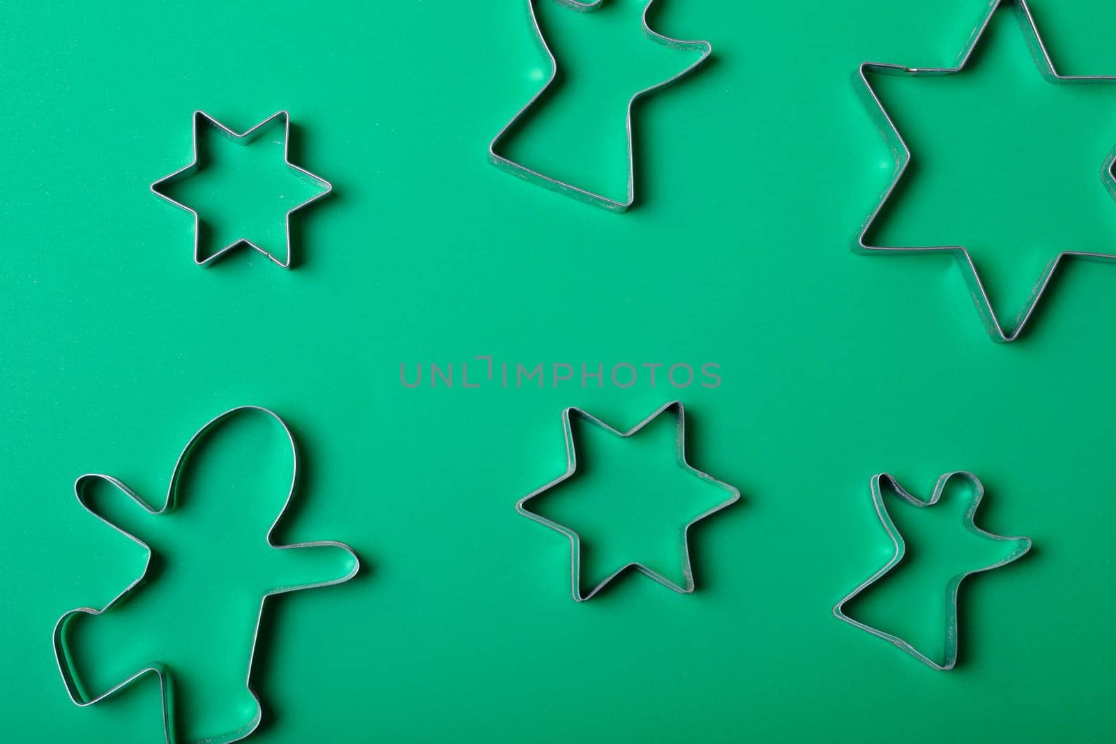 Composition of star and angel ginger man cookie cutters on green background. christmas, tradition and celebration concept.