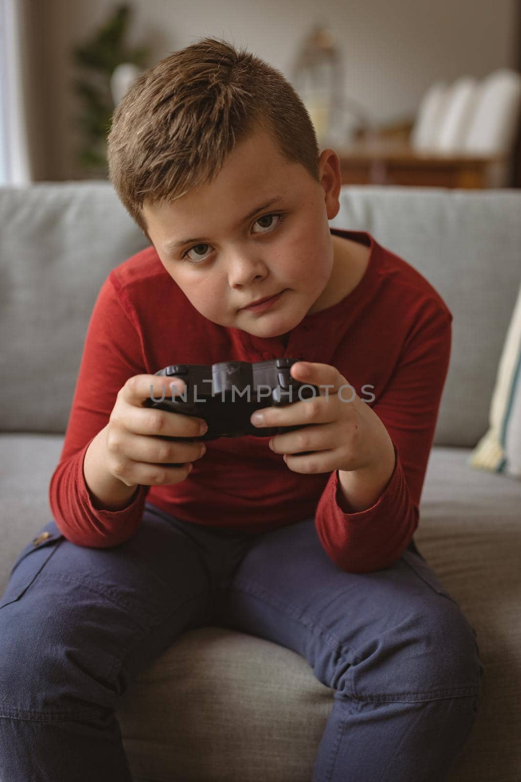 Caucasian boy playing video games sitting on the couch at home. gaming and entertainment concept