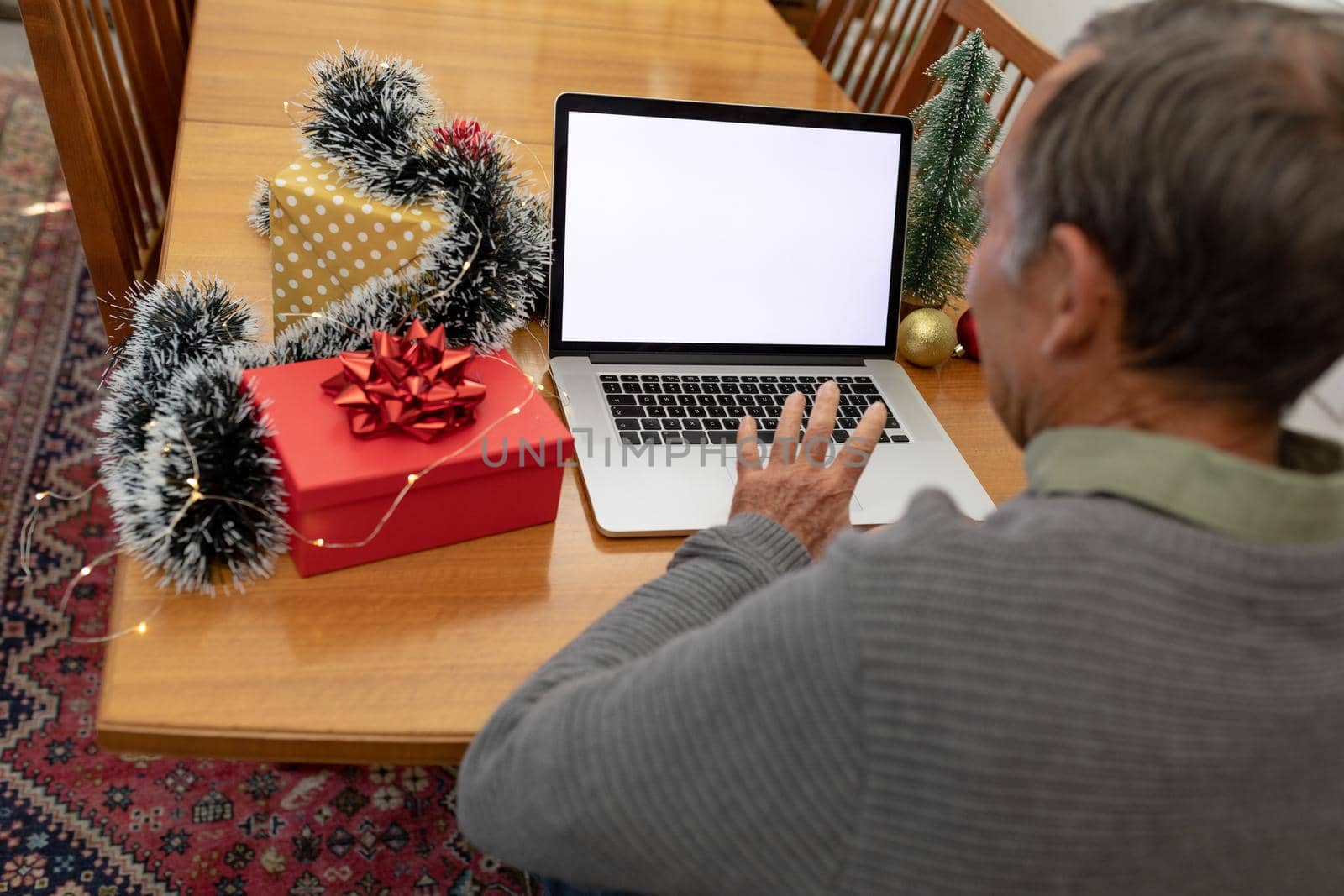 Caucasian senior man having video call on laptop with copy space at christmas time. christmas, festivity and communication technology at home.