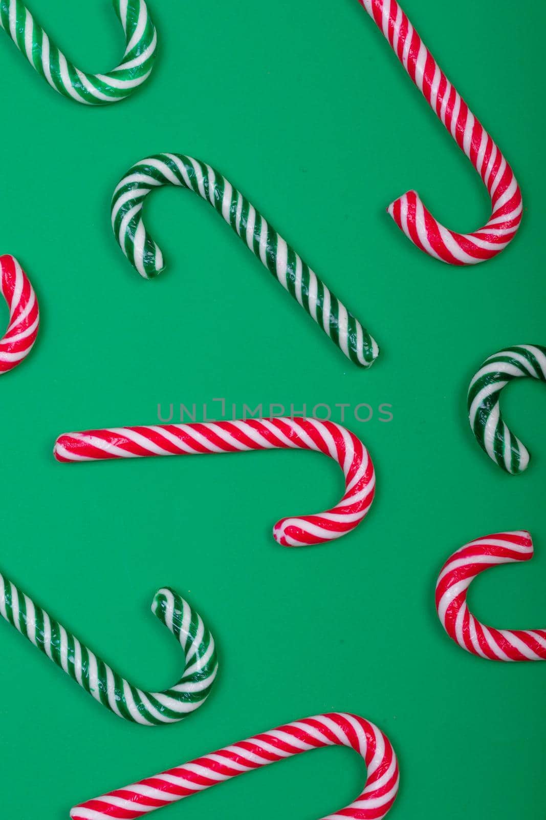 Composition of multiple green and red candy canes on green background. christmas, tradition and celebration concept.