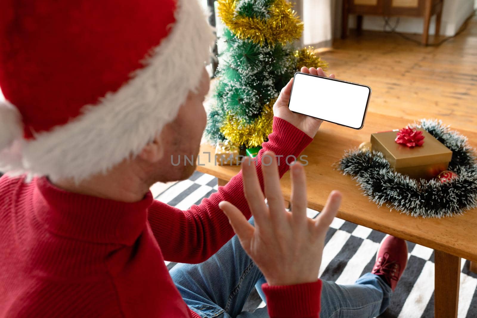 Albino african american man wearing santa hat making video call on smarphone with copy space. christmas, festivity and communication technology festivity and communication technology.