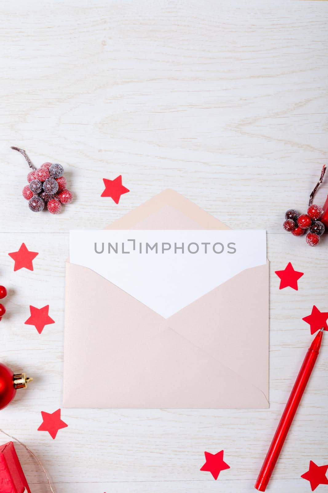 Composition of christmas decorations with envelope and red stars on white wooden background by Wavebreakmedia