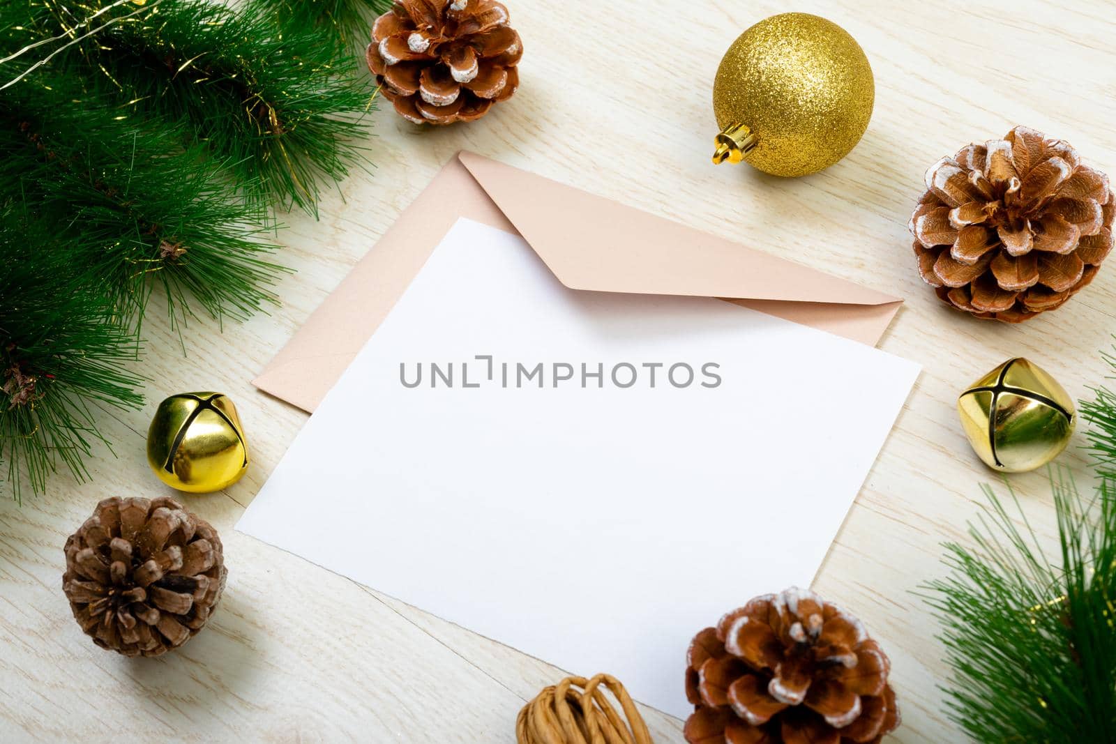 Composition of white card with copy space, envelope and christmas decorations on wooden background by Wavebreakmedia