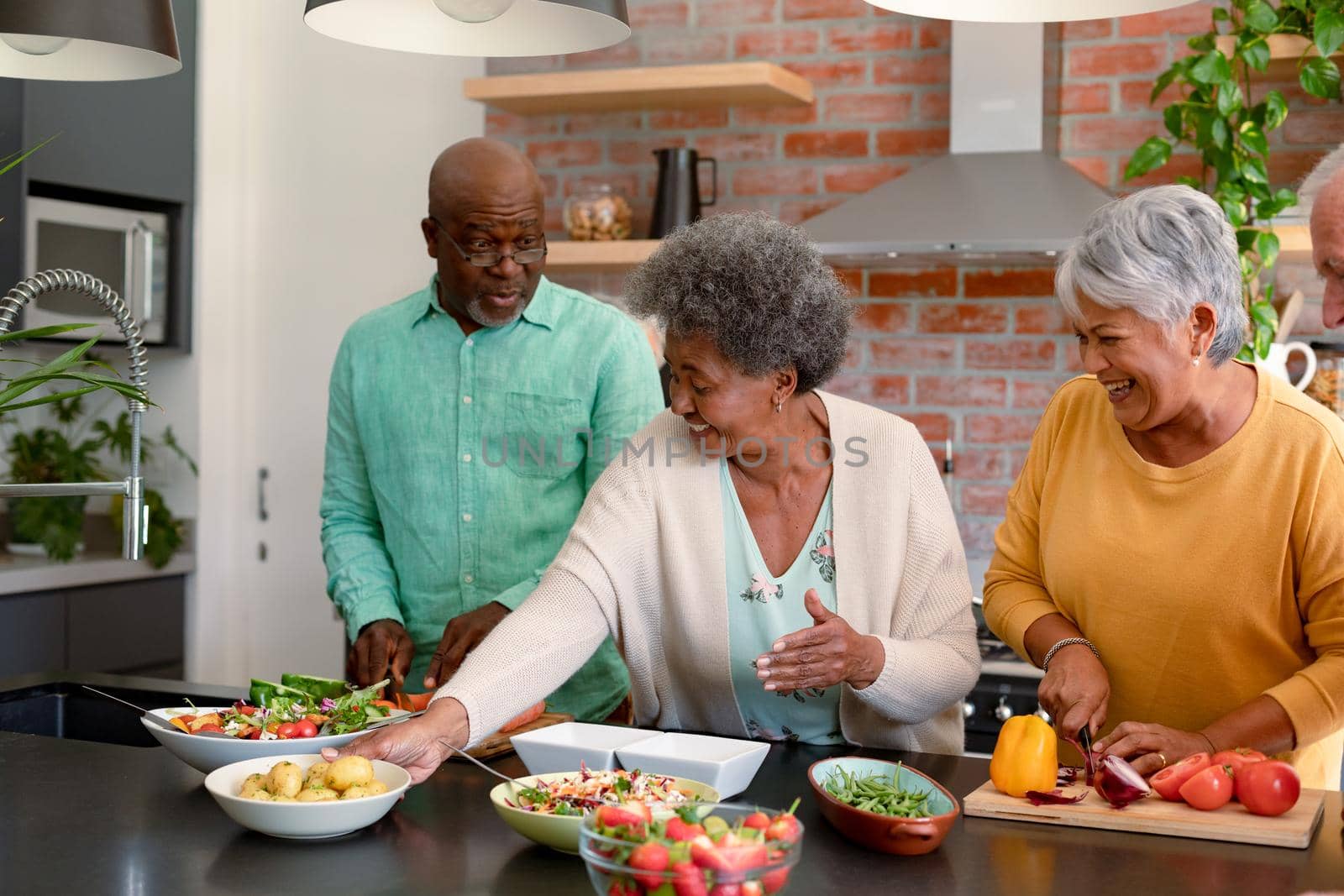 Group of happy diverse senior male and female friends cooking together at home by Wavebreakmedia