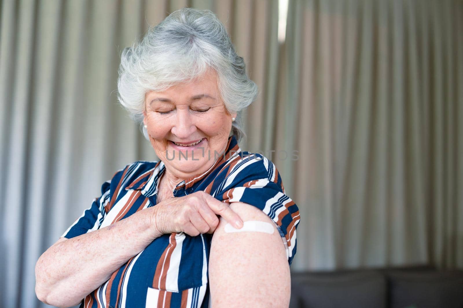 Happy senior caucasian woman showing plaster after vaccination. senior health and lifestyle during covid 19 pandemic.
