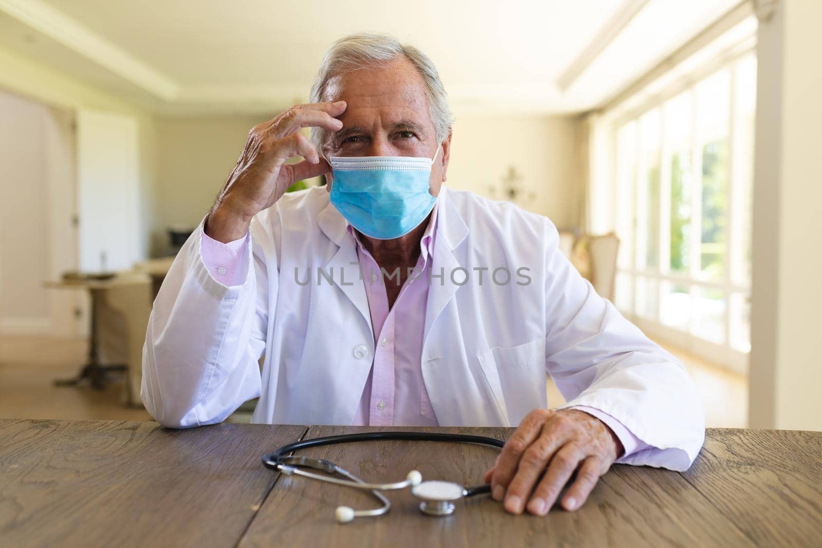 Senior caucasian male doctor wearing face mask having a video call. medicine and healthcare services during covid 19 pandemic concept.