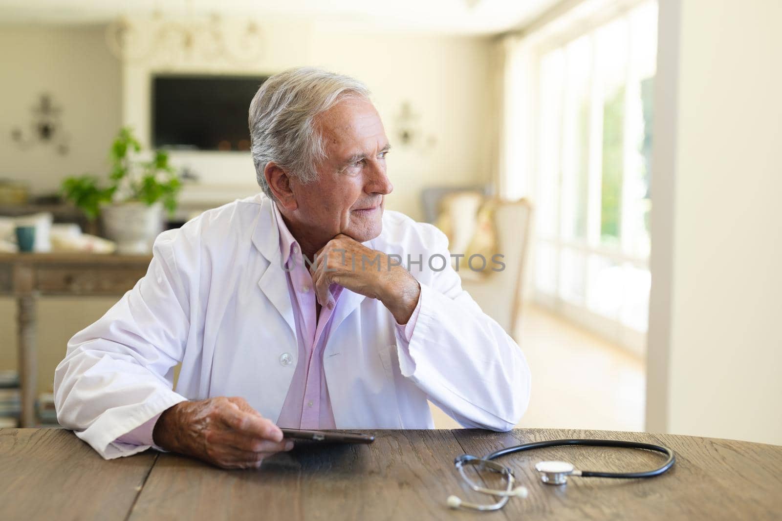 Senior caucasian male doctor sitting at table using tablet computer. medicine and healthcare services concept.