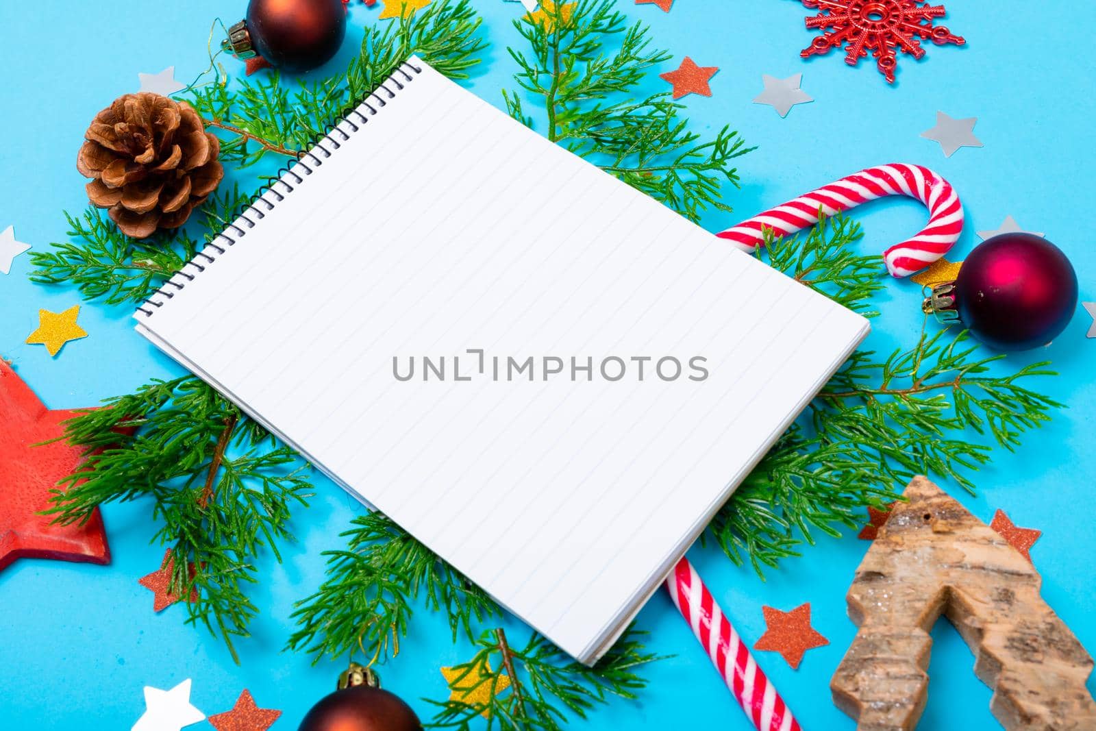 Composition of notebook with copy space and christmas decorations on blue background. christmas, tradition and celebration concept.