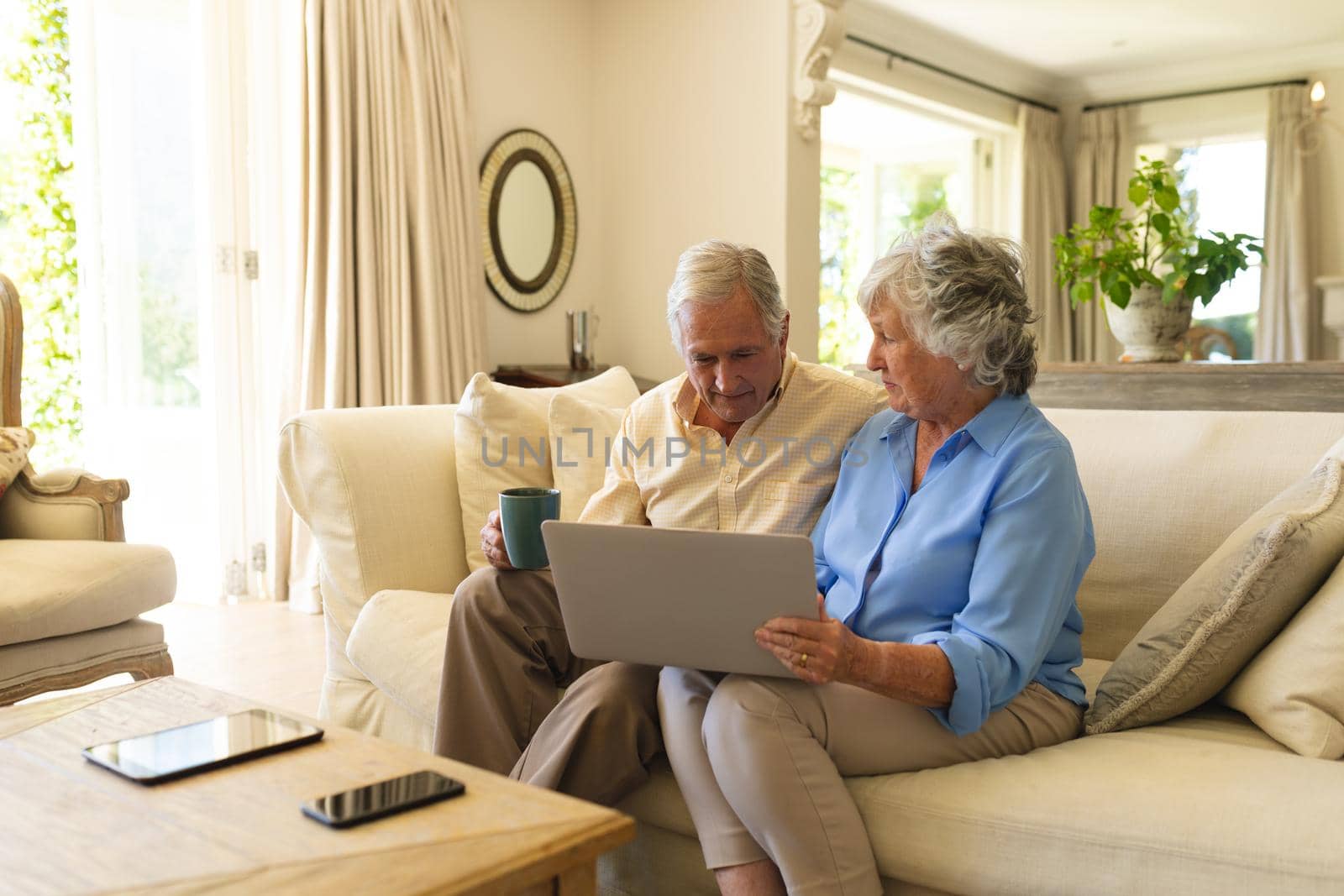 Senior caucasian couple sitting on sofa using laptop by Wavebreakmedia