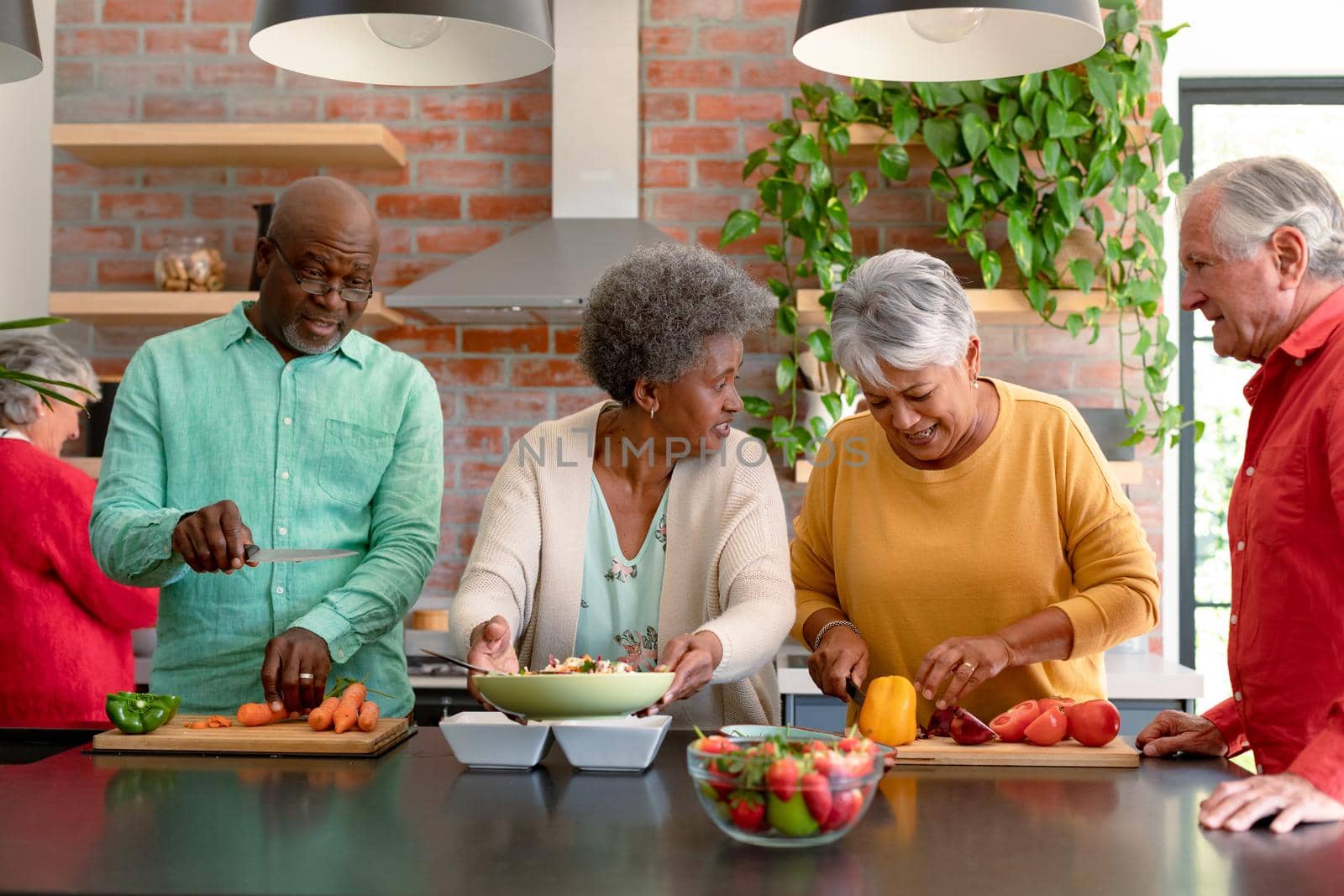 Group of happy diverse senior male and female friends cooking together at home. cooking and socialising with friends at home.