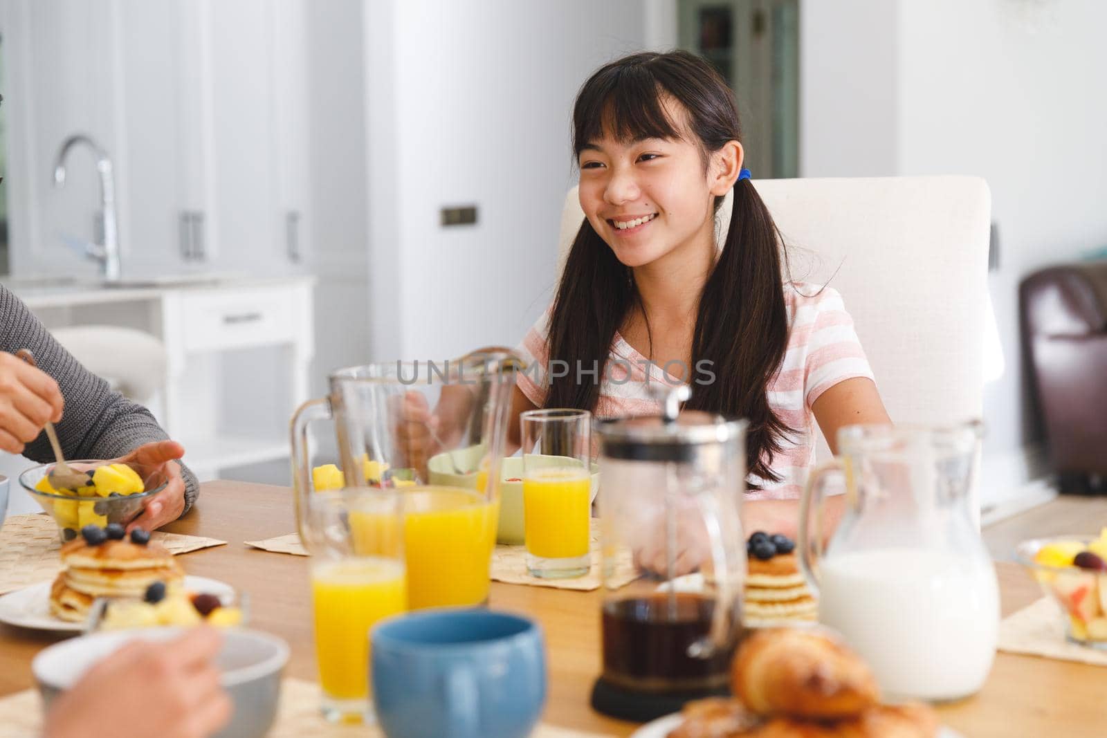 Smiling asian daughter sitting at table having breakfast with father by Wavebreakmedia