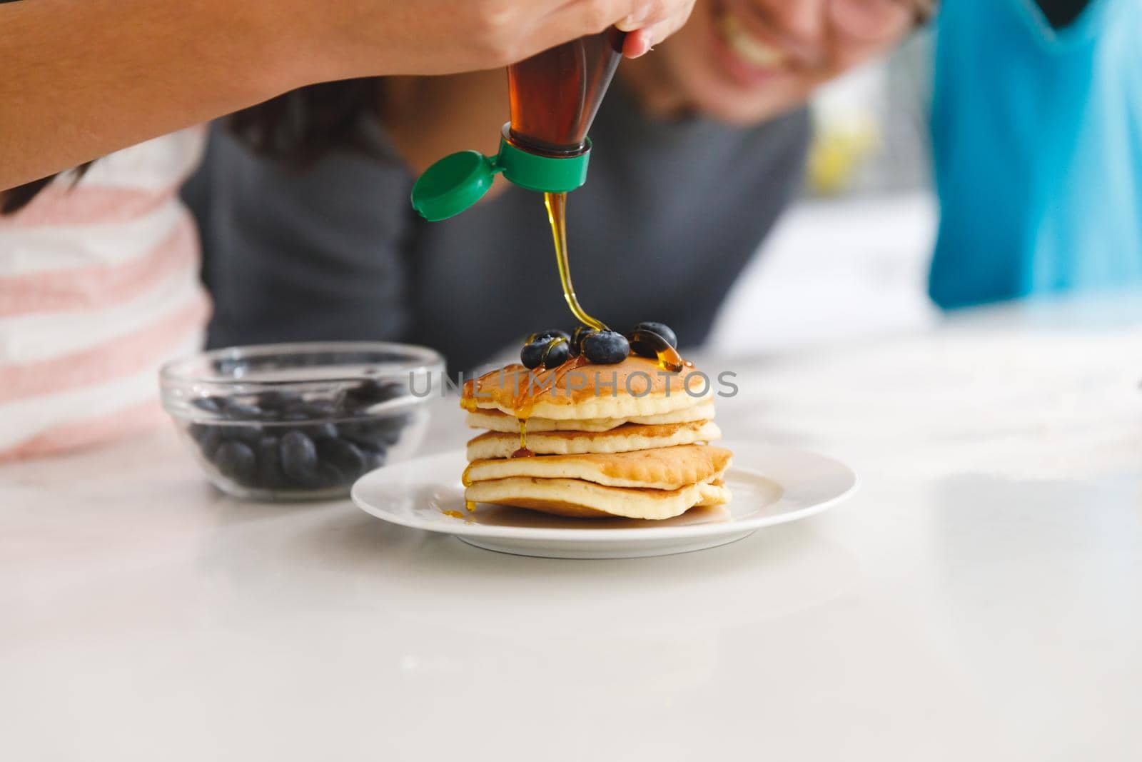 Asian father watching daughter preparing breakfast pancakes in kitchen by Wavebreakmedia