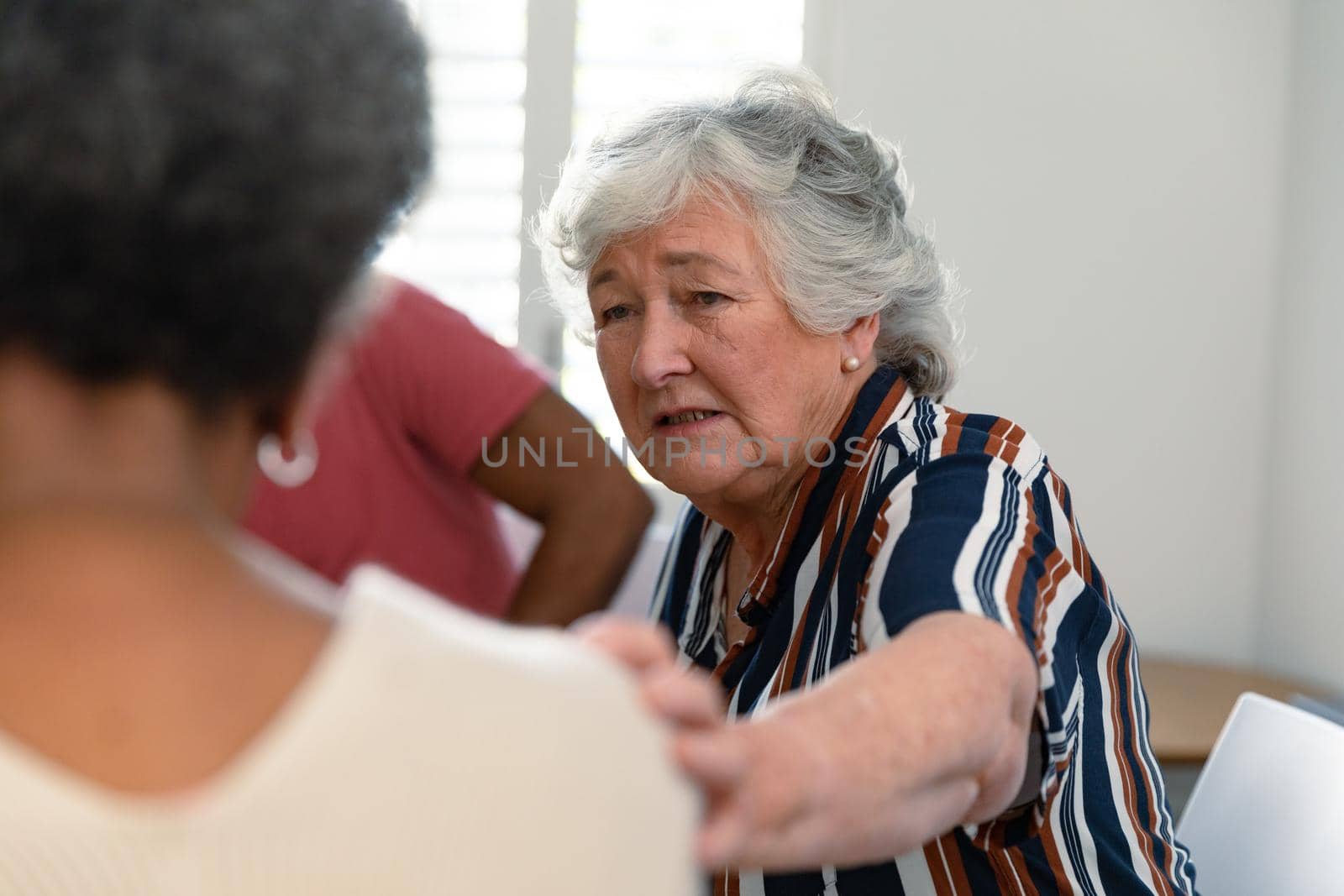 Caucasian senior woman touching african american female friend and supporting her by Wavebreakmedia