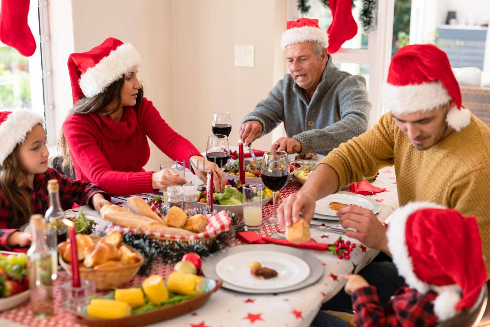 Caucasian multi generation family wearing santa hats having christmas meal by Wavebreakmedia
