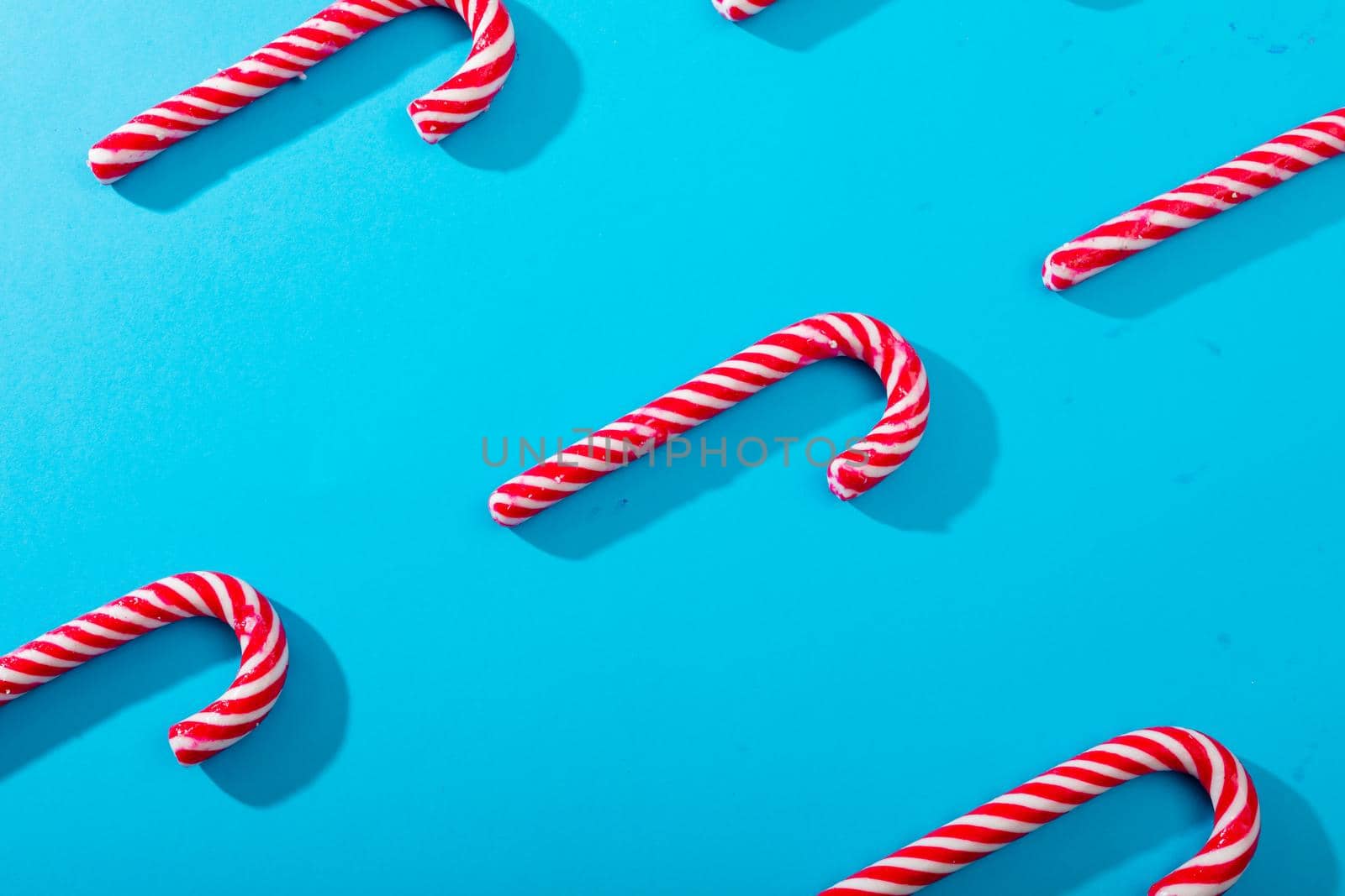 Composition of multiple rows of candy canes on blue background by Wavebreakmedia