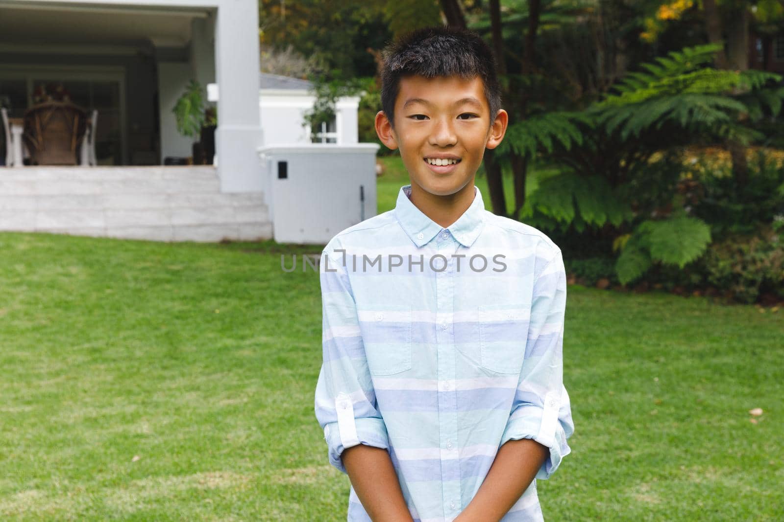 Portrait of smiling asian boy smiling outdoors and wearing casual clothes in garden. enjoying leisure time alone at home.