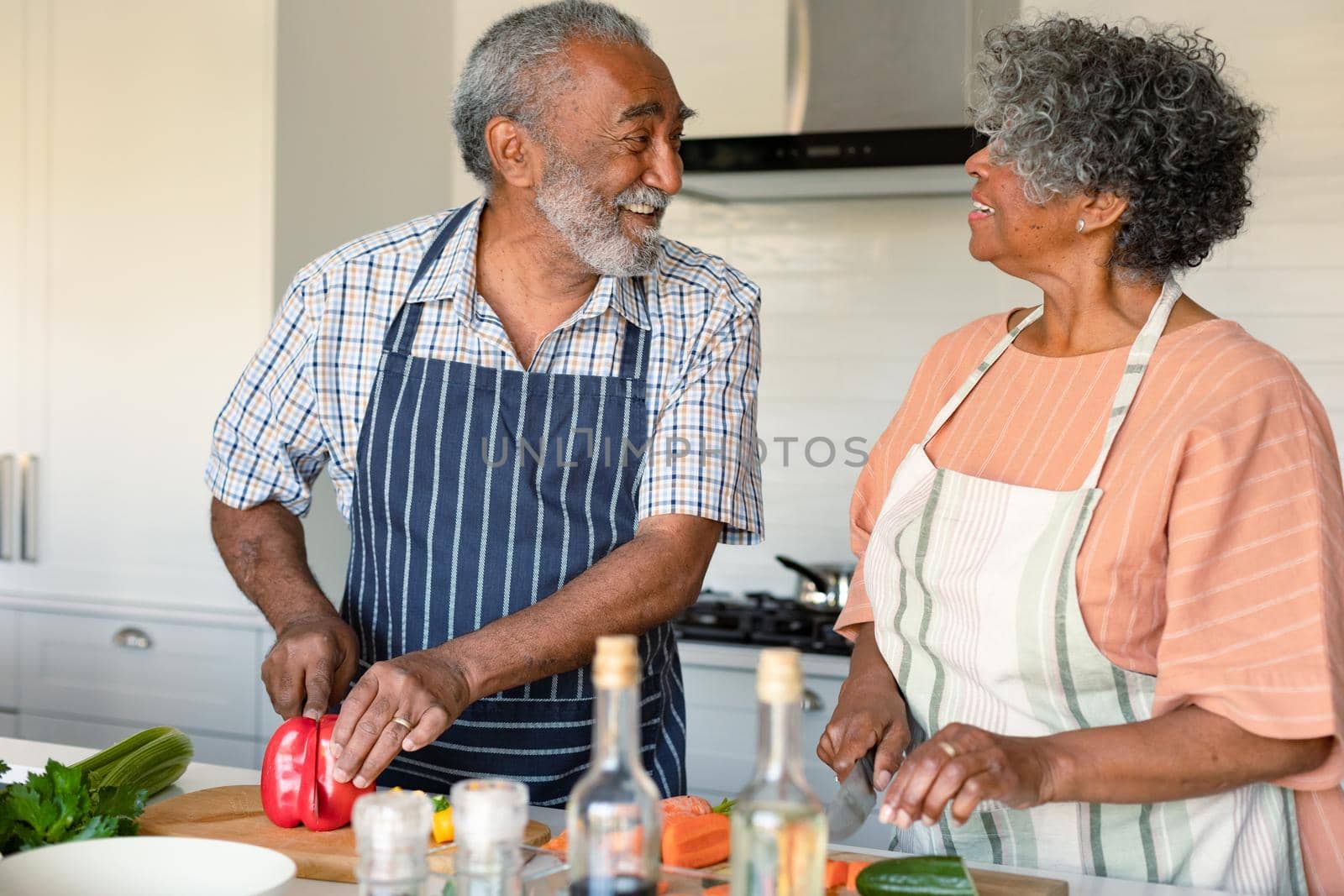 Happy arfican american senior couple cutting vegetables and preparing meal together by Wavebreakmedia