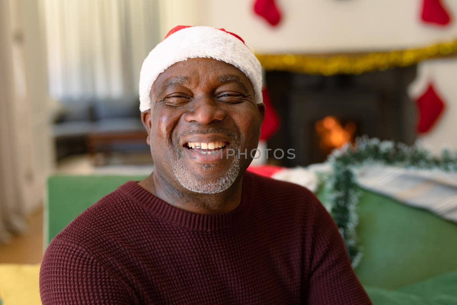 Happy african american senior man in santa hat looking at camera at christmas time by Wavebreakmedia