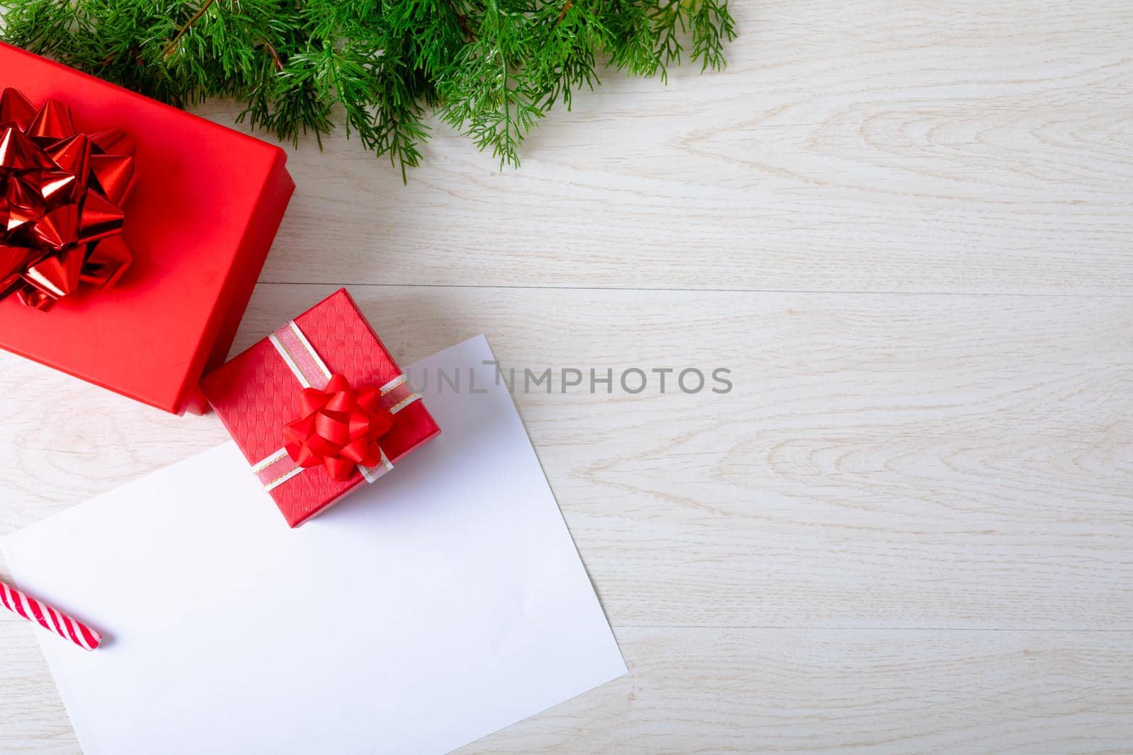 Composition of white card with copy space and fir tree branches with presents on wooden background. christmas, tradition and celebration concept.