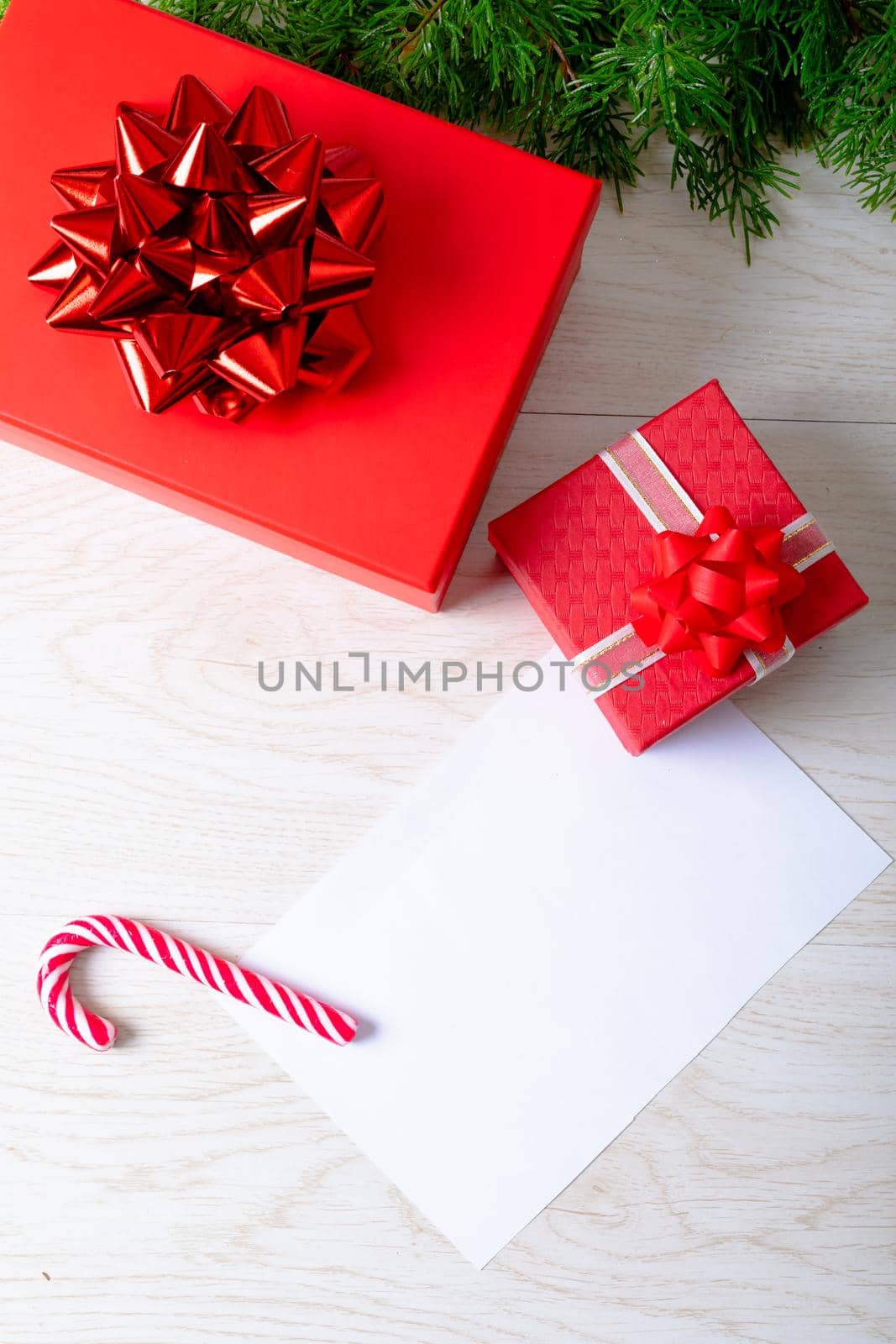 Composition of white card with copy space and fir tree branches with presents on wooden background by Wavebreakmedia