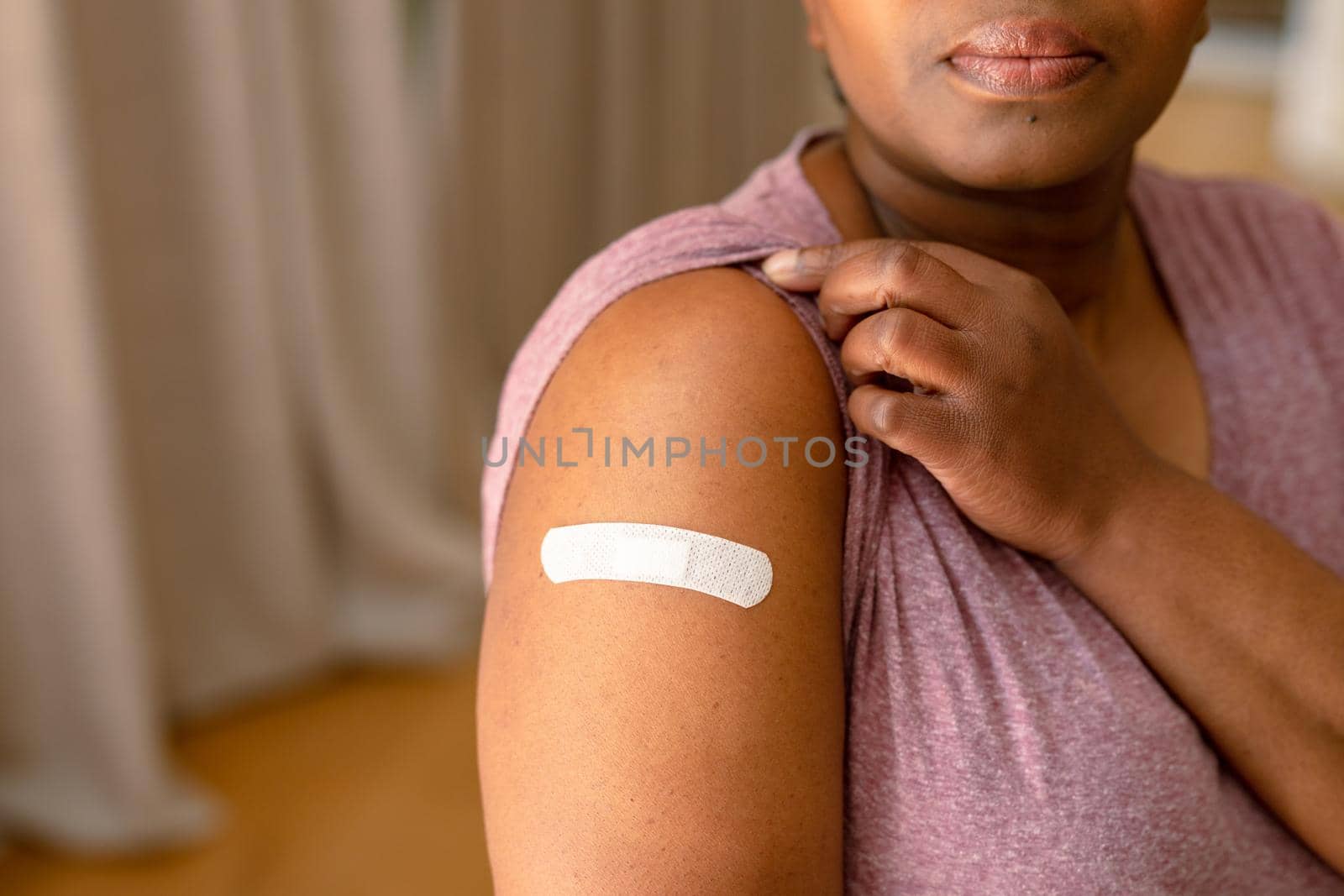 African american senior woman showing plaster after vaccination. senior health and lifestyle during covid 19 pandemic.