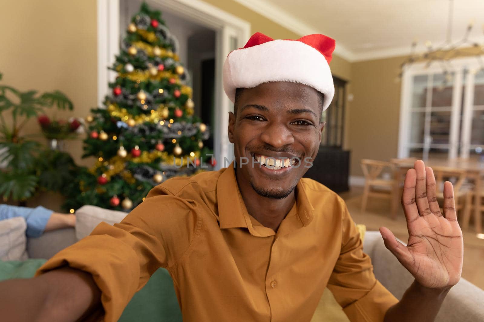 Happy african american man in santa hats having video call at christmas time. christmas, festivity and communication technology.
