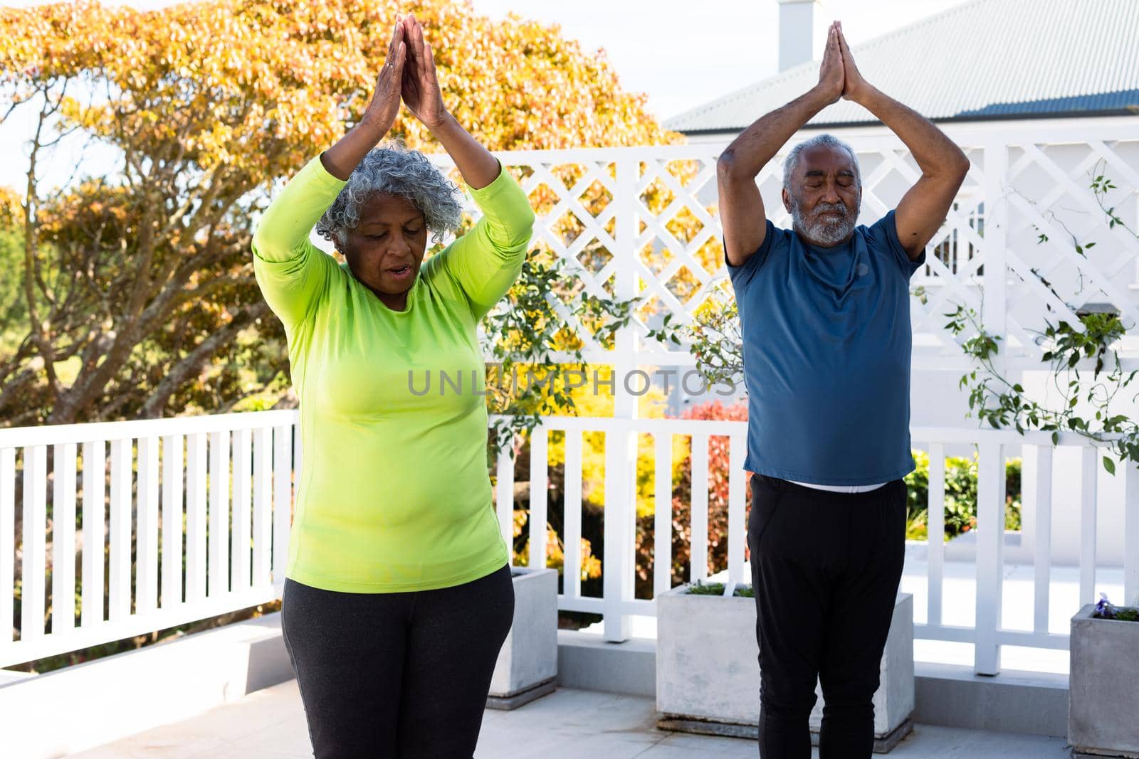 Focused african american senior couple practicing yoga in garden. active and healthy retirement lifestyle at home.