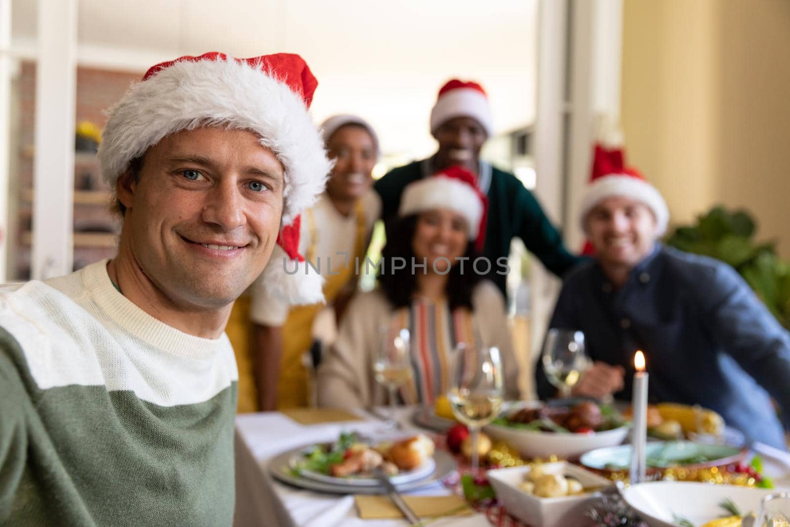 Happy caucasian man in santa hat taking selfie, celebrating christmas with friends at home by Wavebreakmedia