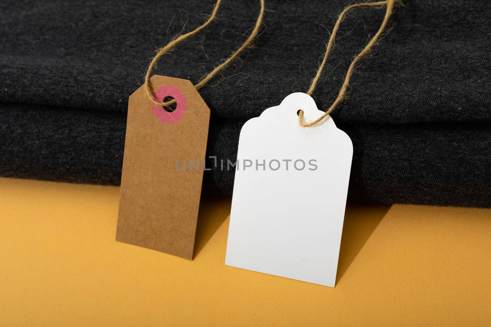 Composition of gift tags with copy space and black fabric on yellow background. christmas, gifts, tradition and celebration concept.
