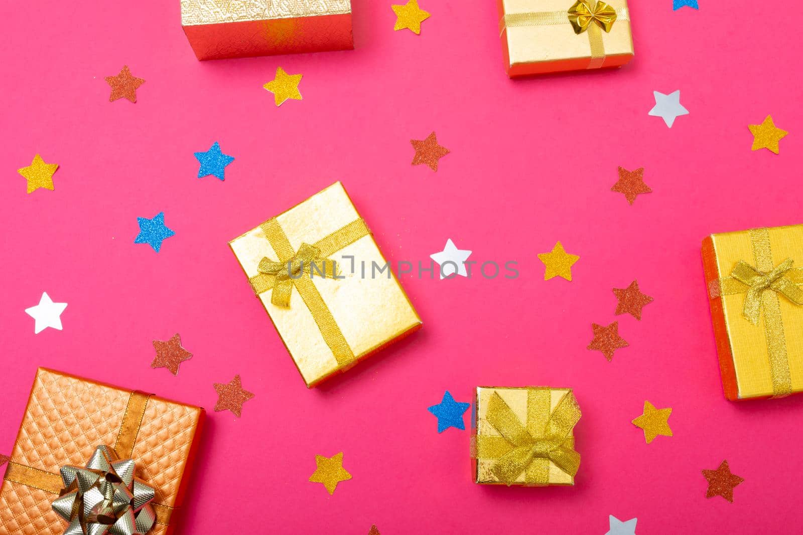 Composition of christmas decorations with presents and stars on pink background. christmas, tradition and celebration concept.