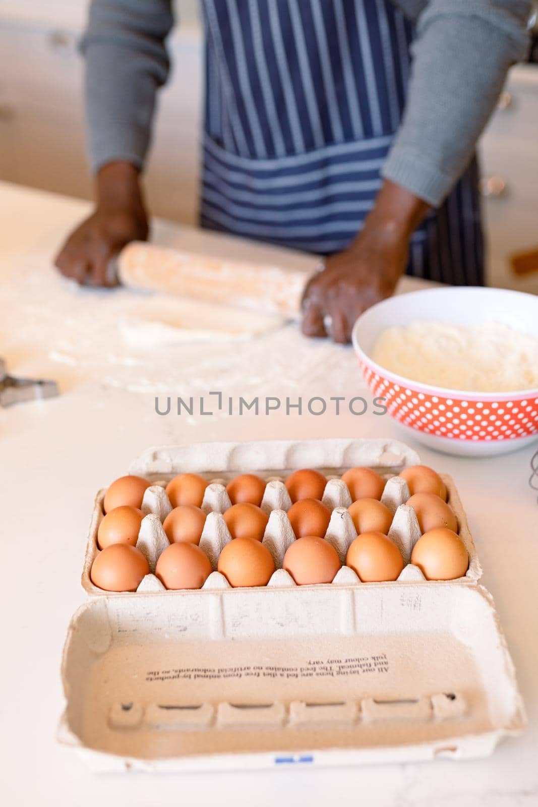Midsection of african american man wearing apron, baking in kitchen by Wavebreakmedia