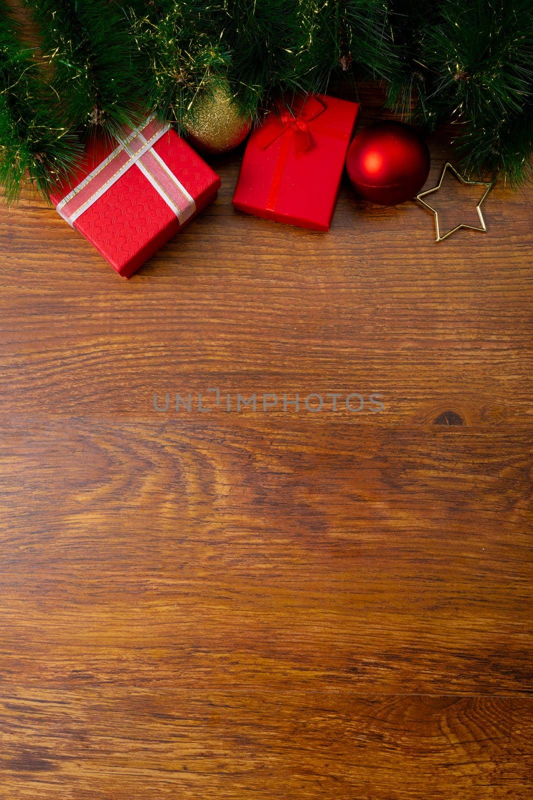 Composition of christmas decorations with presents, baubles and copy space on wooden background by Wavebreakmedia