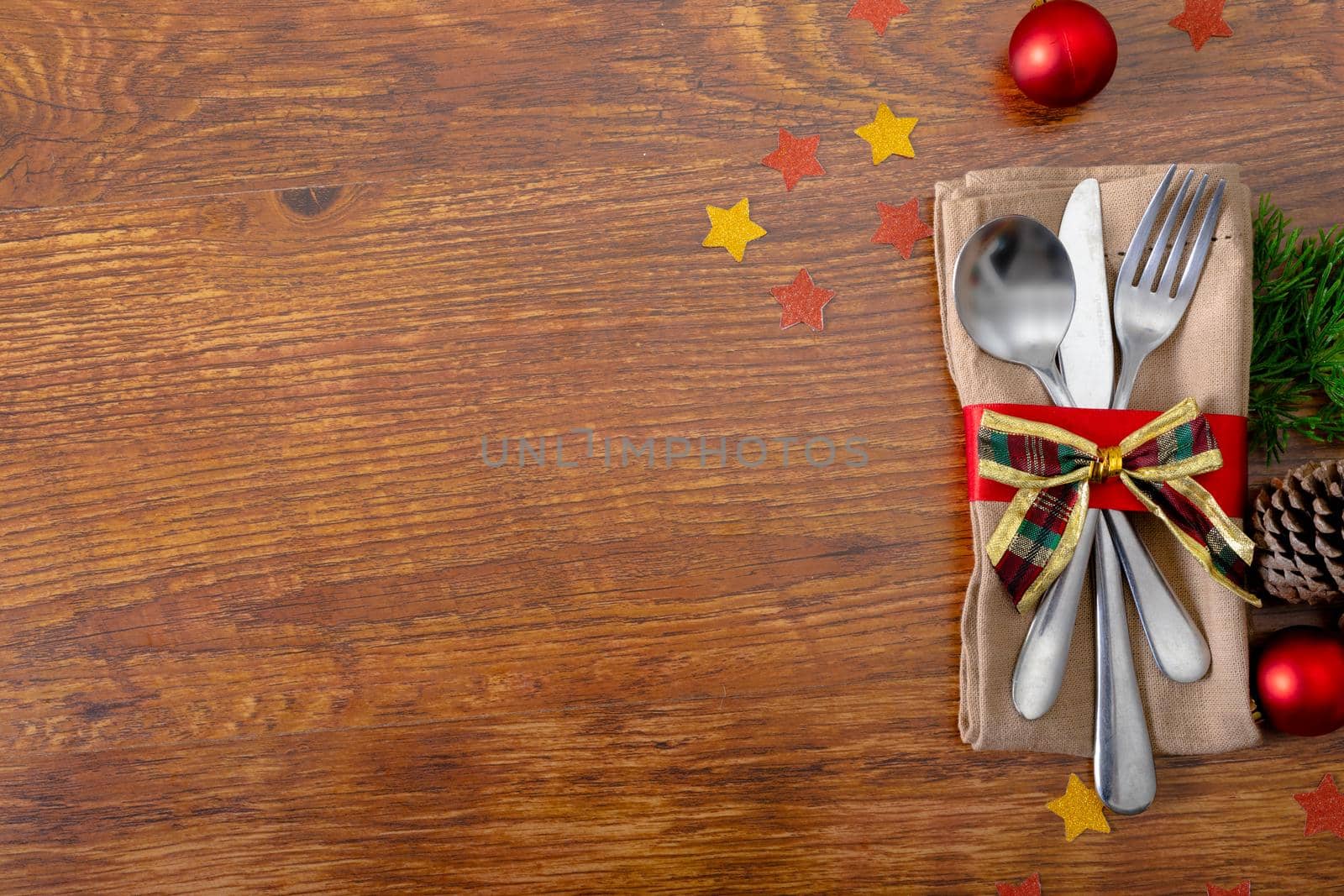 Composition of christmas decorations with cutlery and copy space on wooden background. christmas, tradition and celebration concept.
