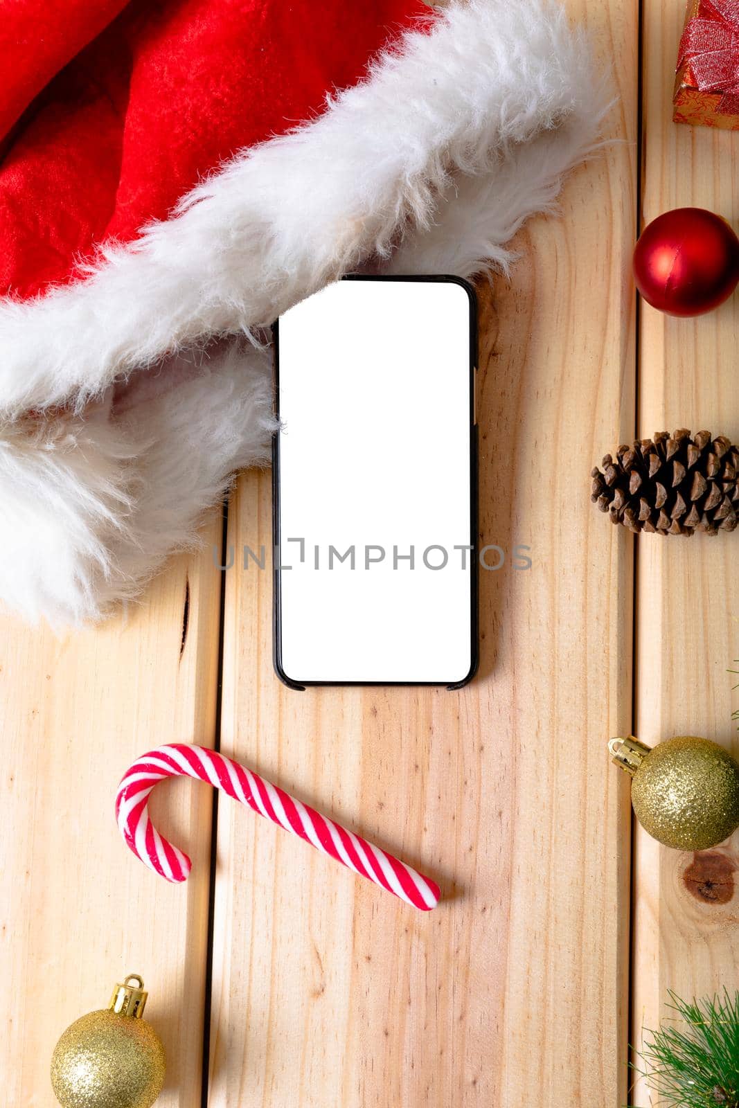 Composition of smartphone with copy space and christmas decorations on wooden background. christmas, tradition and celebration concept.