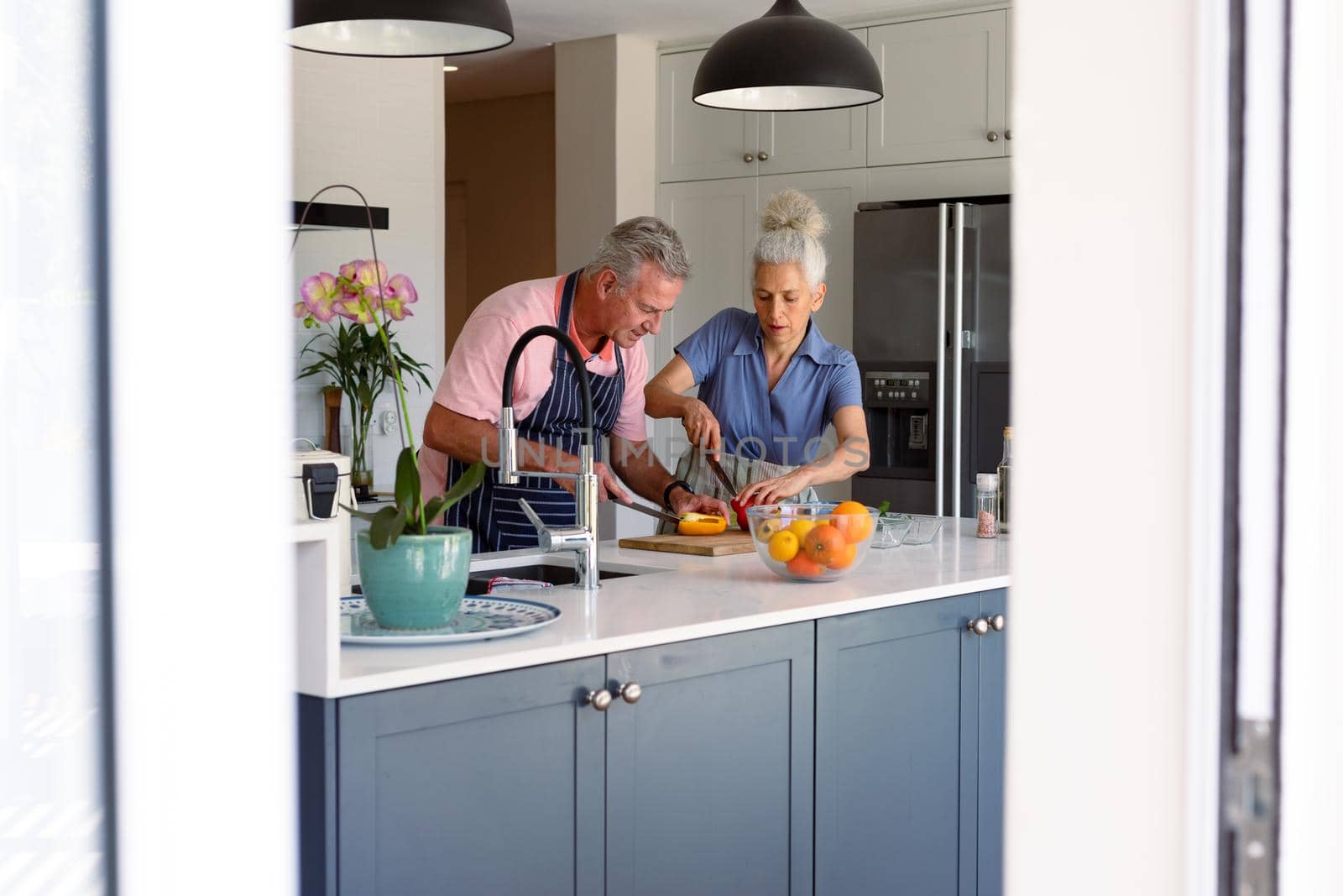 Focused caucasian senior couple standing in kitchen and preparing meal together by Wavebreakmedia